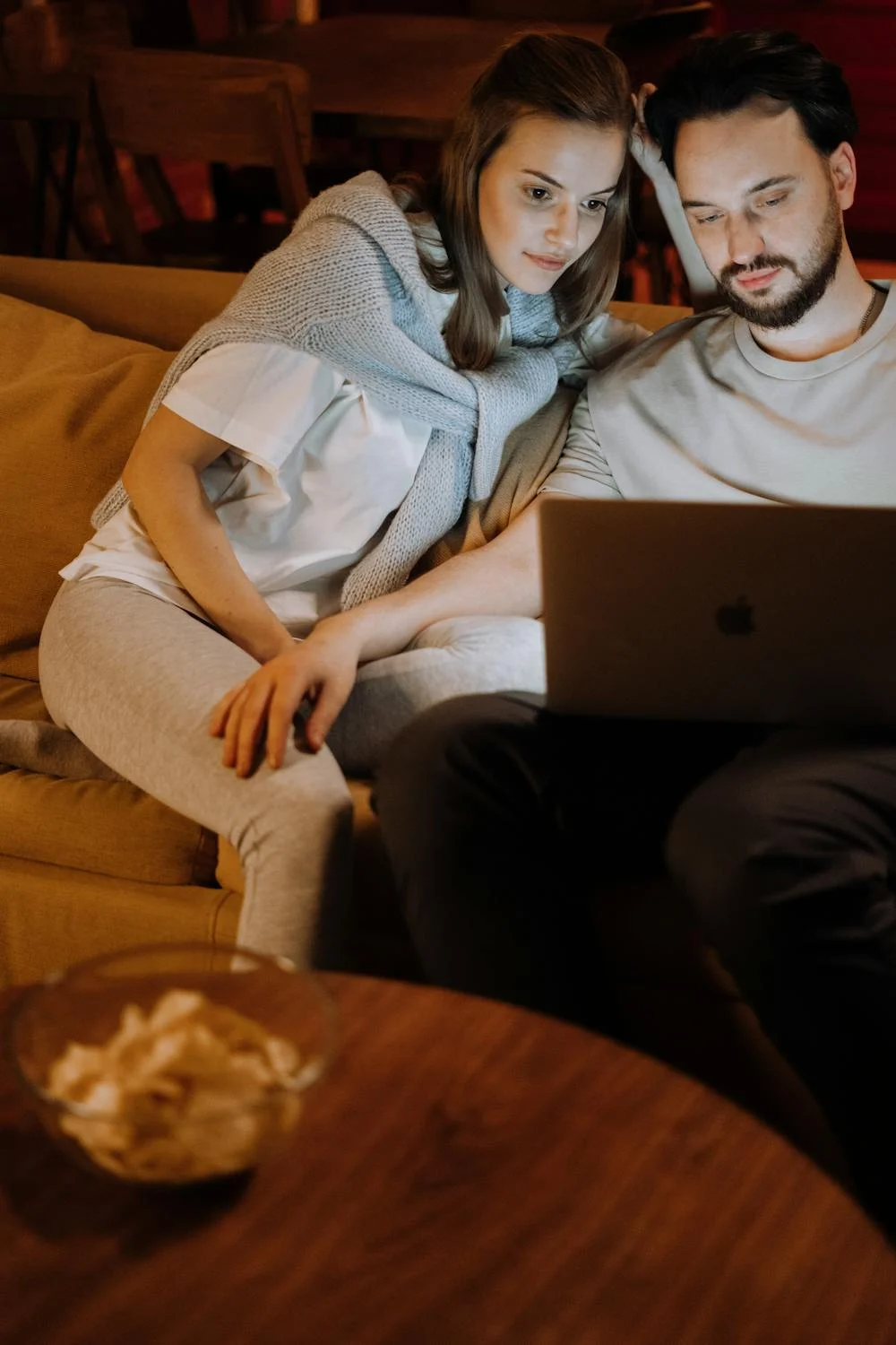 A happy couple watching a movie on their couch ⏐ Source: Pexels