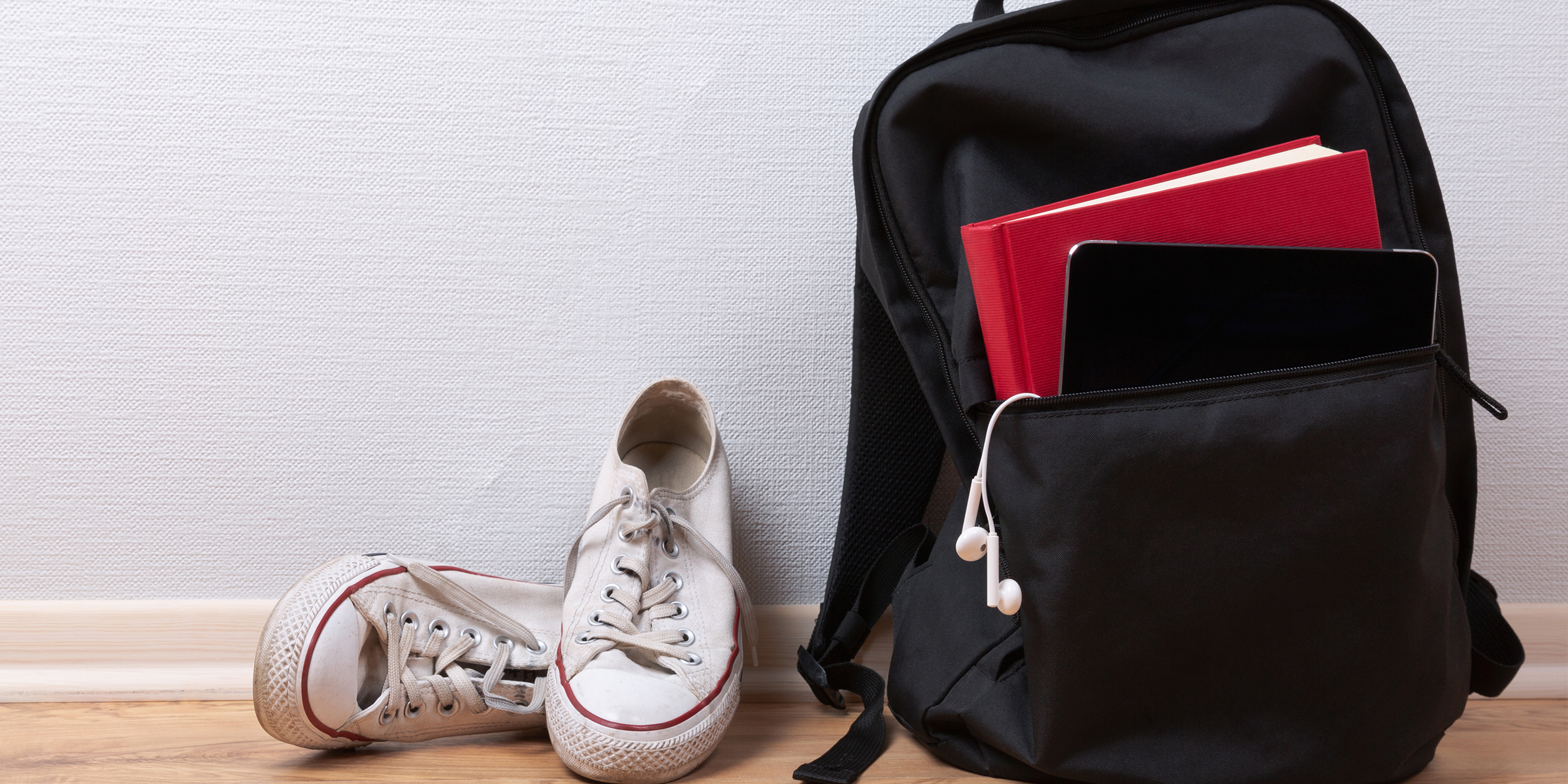 A black backpack next to a pair of white sneakers | Source: Shutterstock