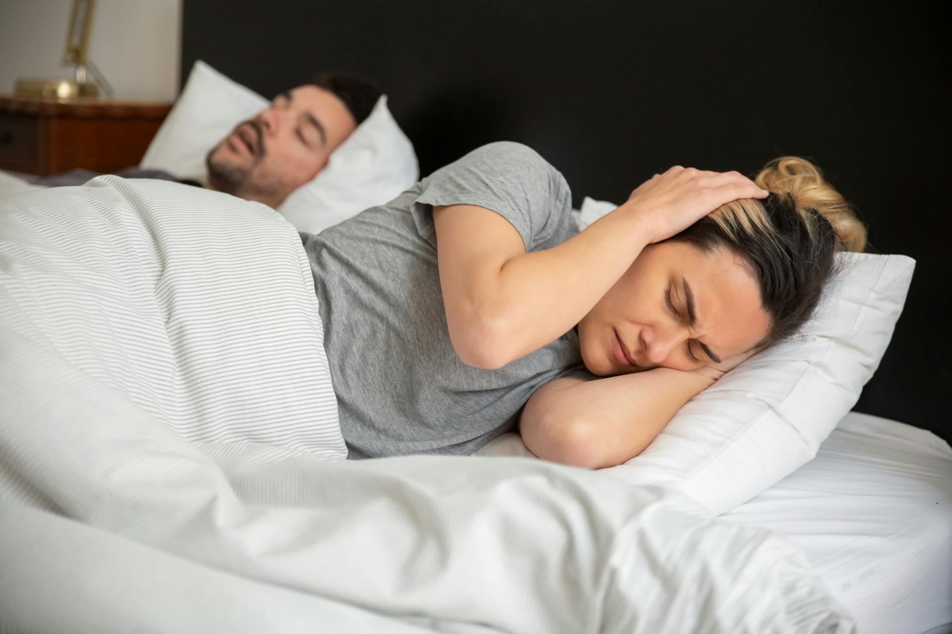 A woman in bed covering her ears with her hands | Source: Pexels