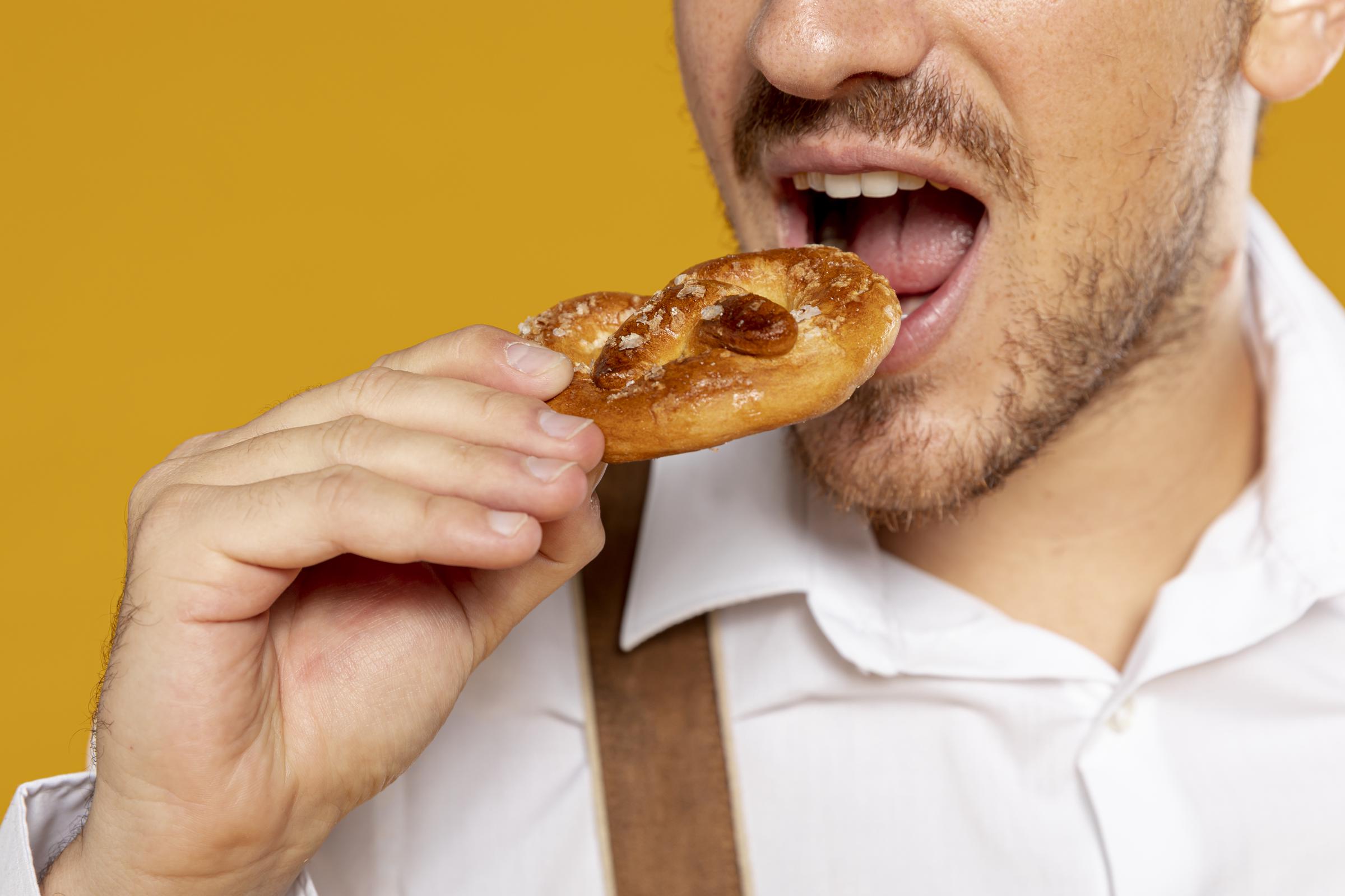 Close-up of a man eating a pretzel | Source: Freepik