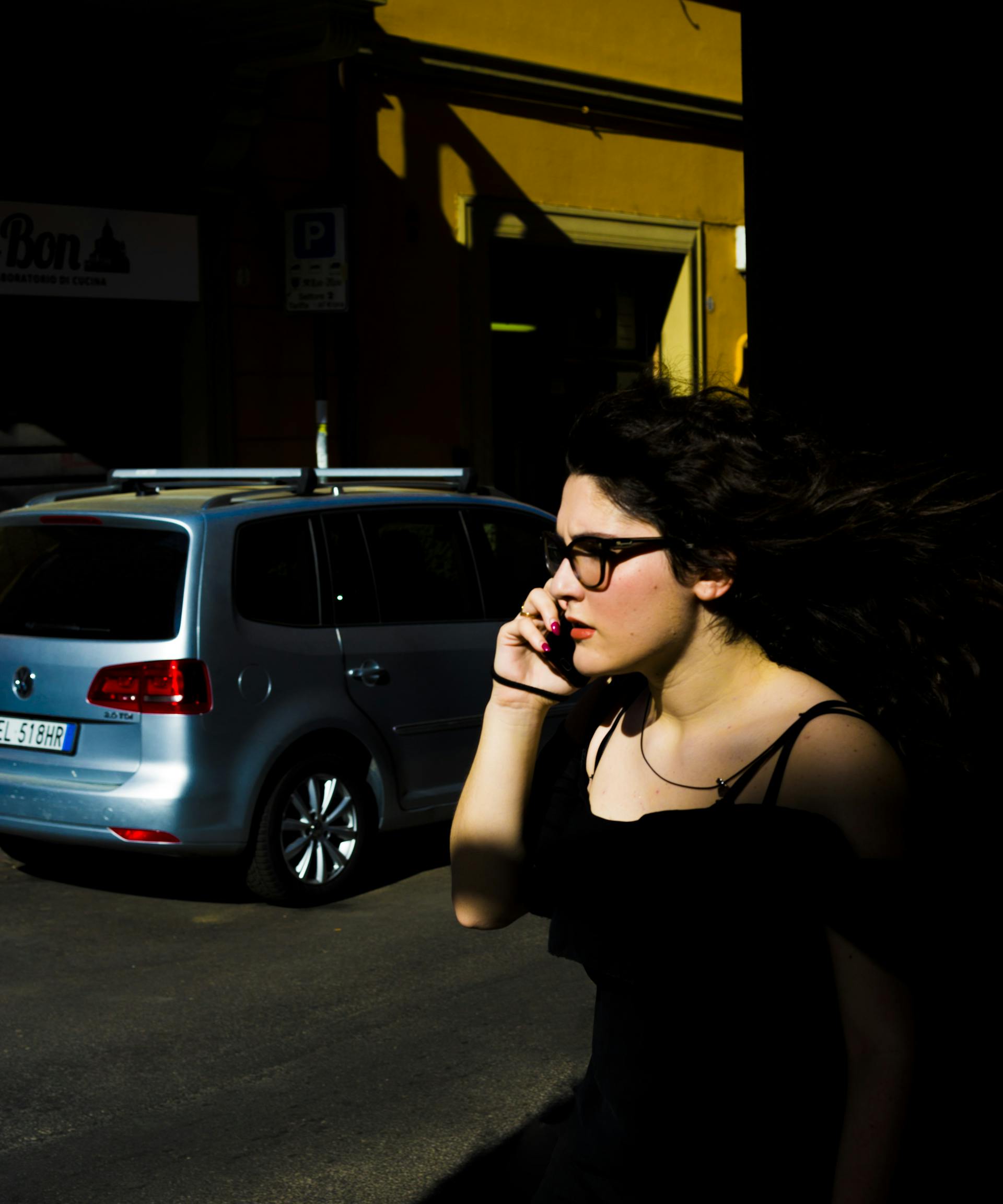 A woman standing near a parked vehicle talking on her phone | Source: Pexels