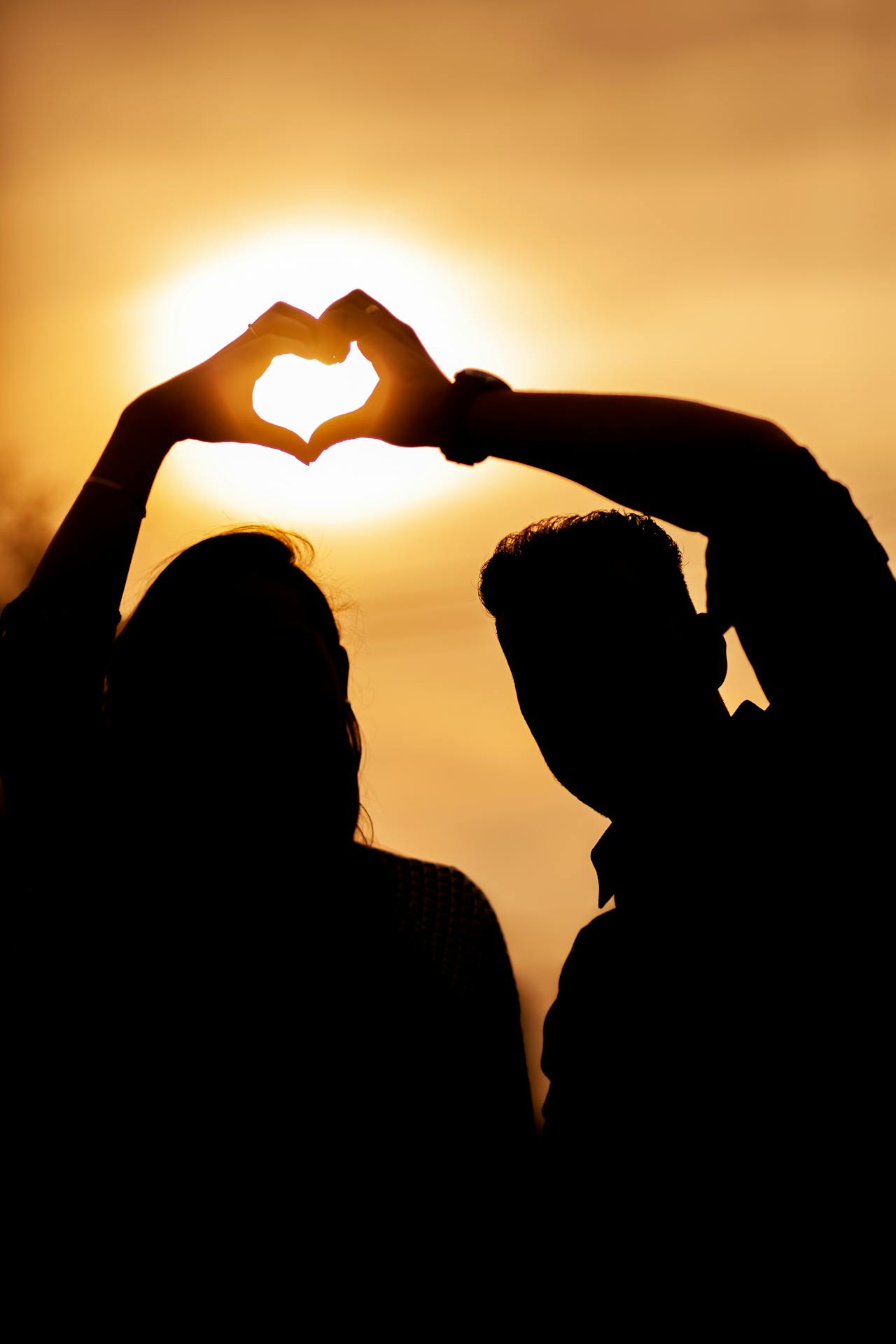 Silhouette of a couple making a hand heart gesture | Source: Pexels