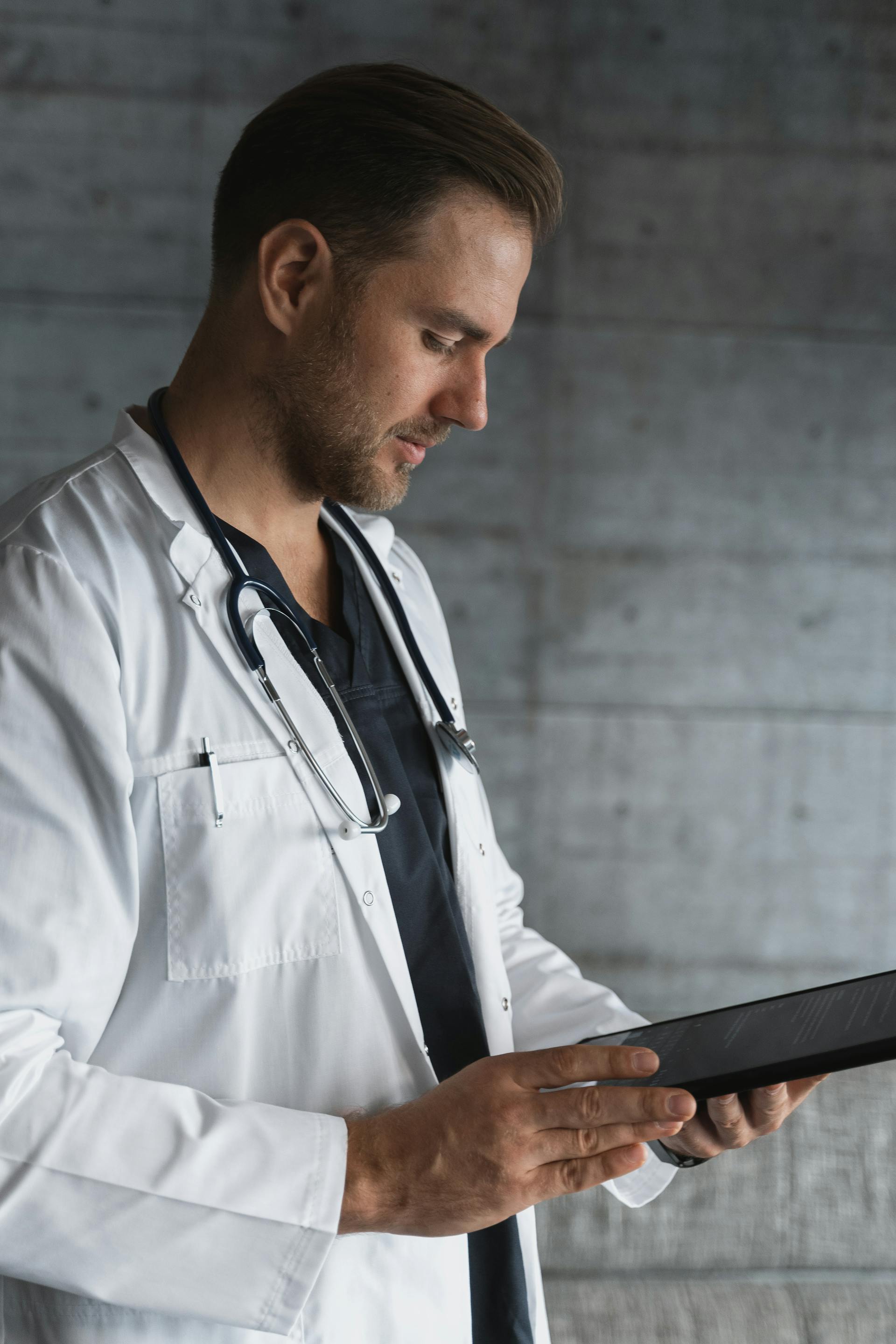 A doctor reading information on a clipboard | Source: Pexels