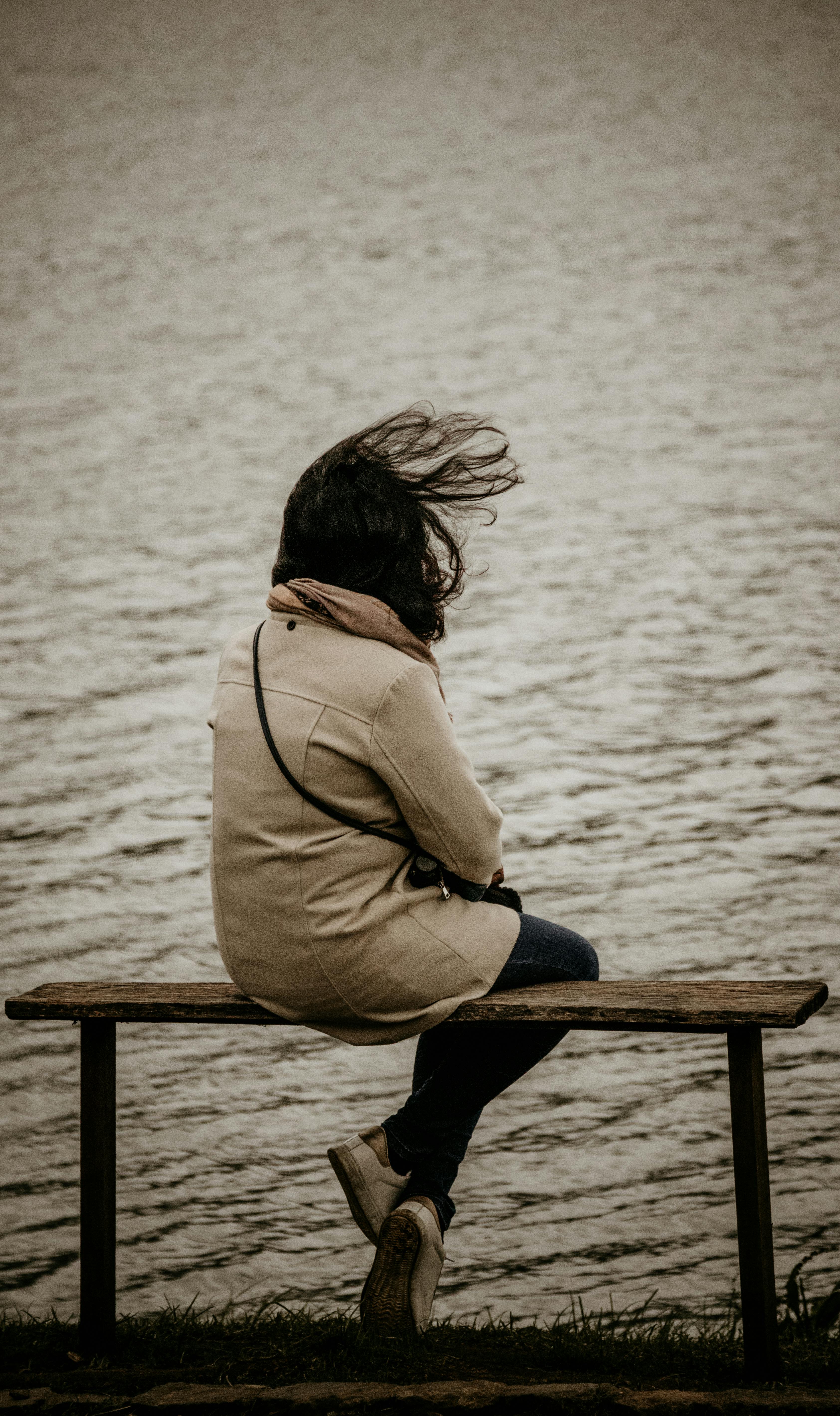 Woman sitting on a bench by the lake | Source: Pexels