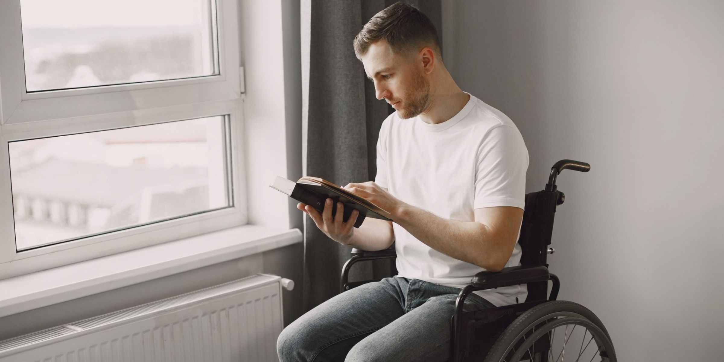 Man reading a book while sitting in a wheelchair | Source: Pexels