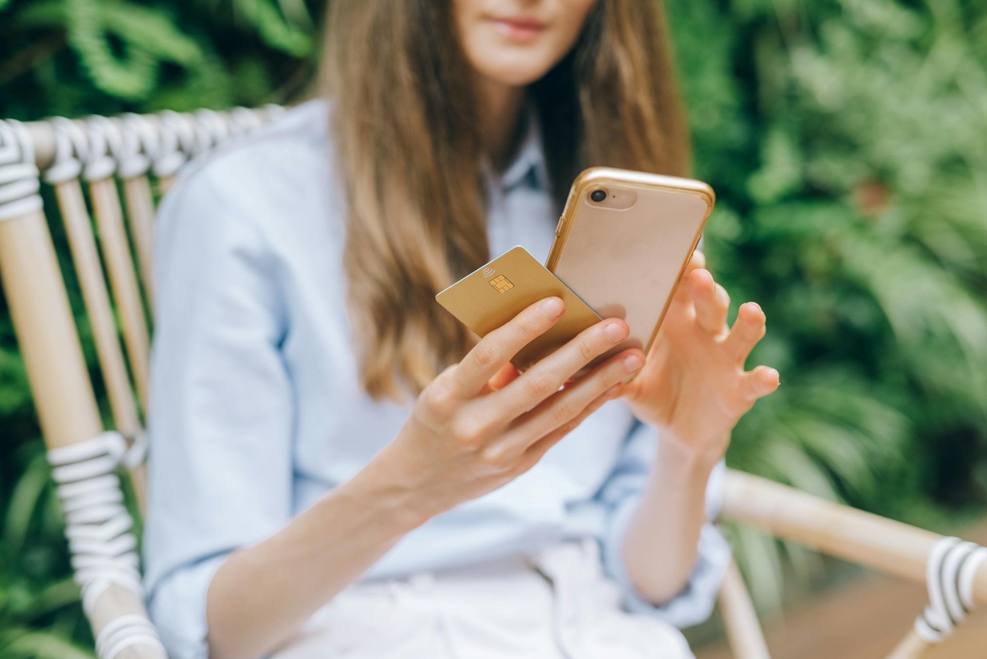 A woman holding a smartphone and a credit card | Source: Pexels