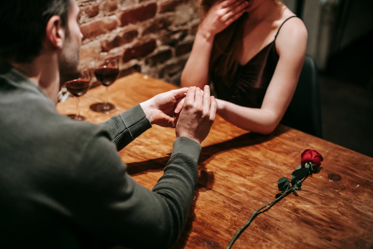 A man holding a woman's hand during their dinner date | Source: Pexels
