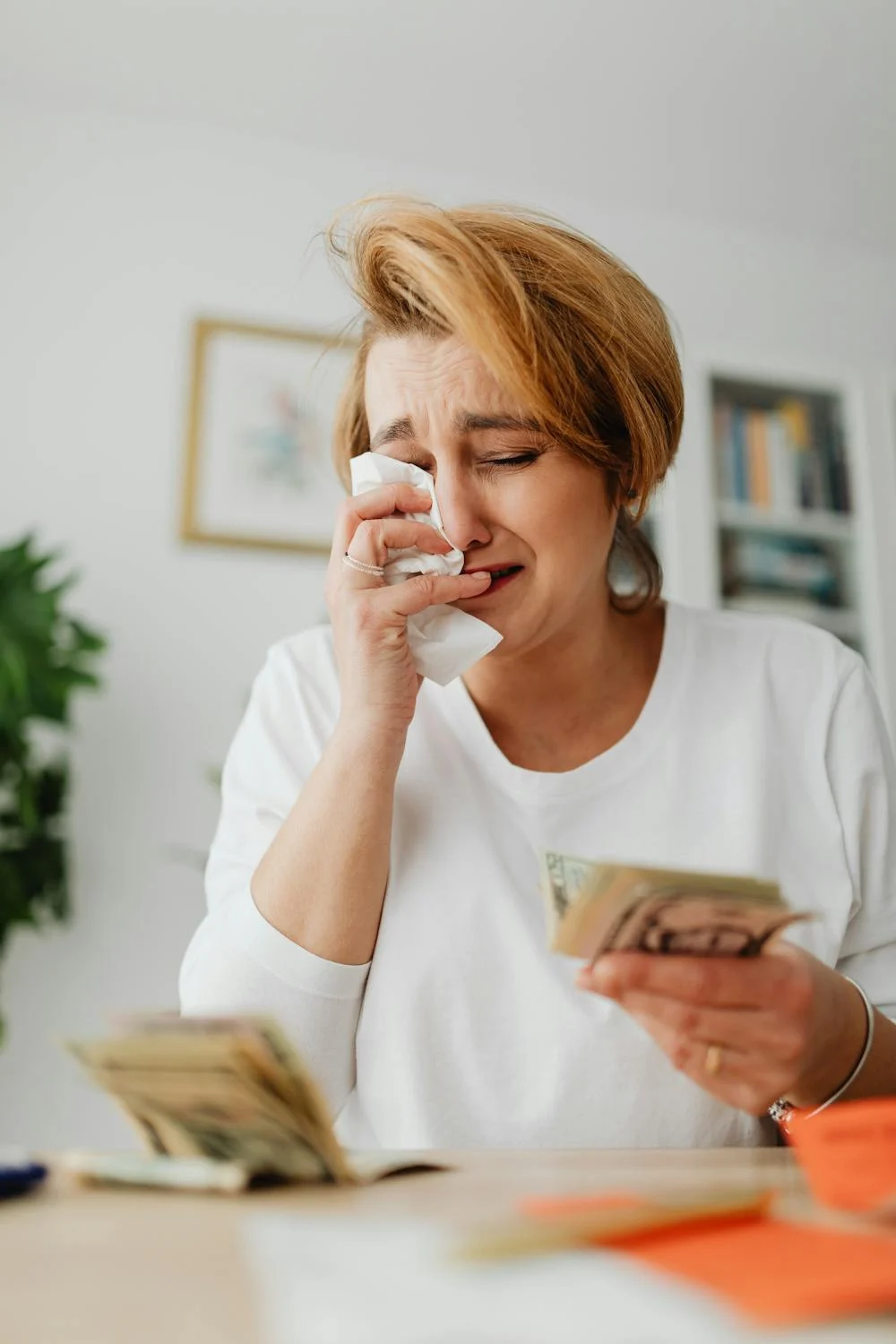 A woman crying while holding money | Source: Pexels