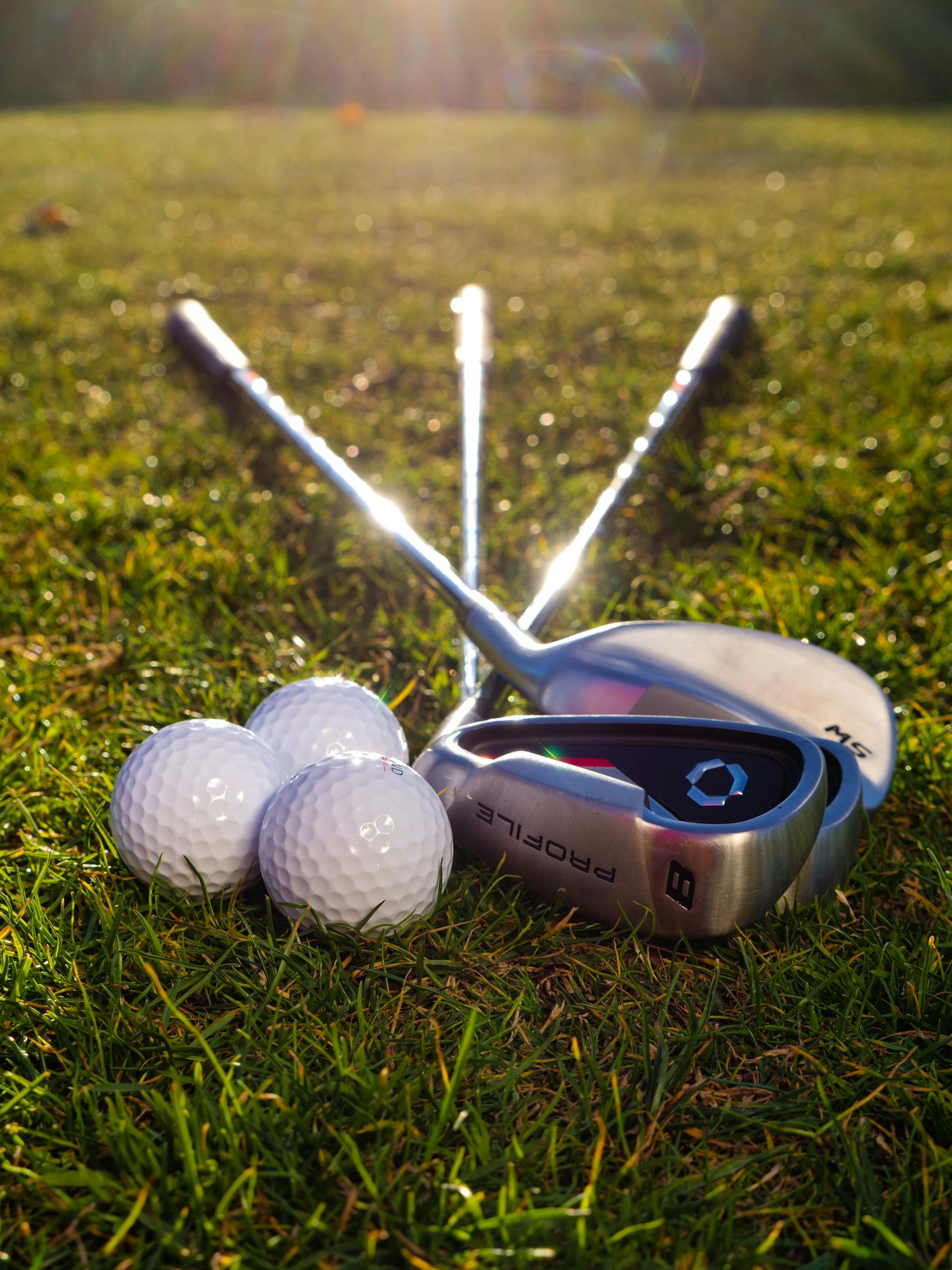 Golf balls and golf clubs lying on the grass | Source: Pexels
