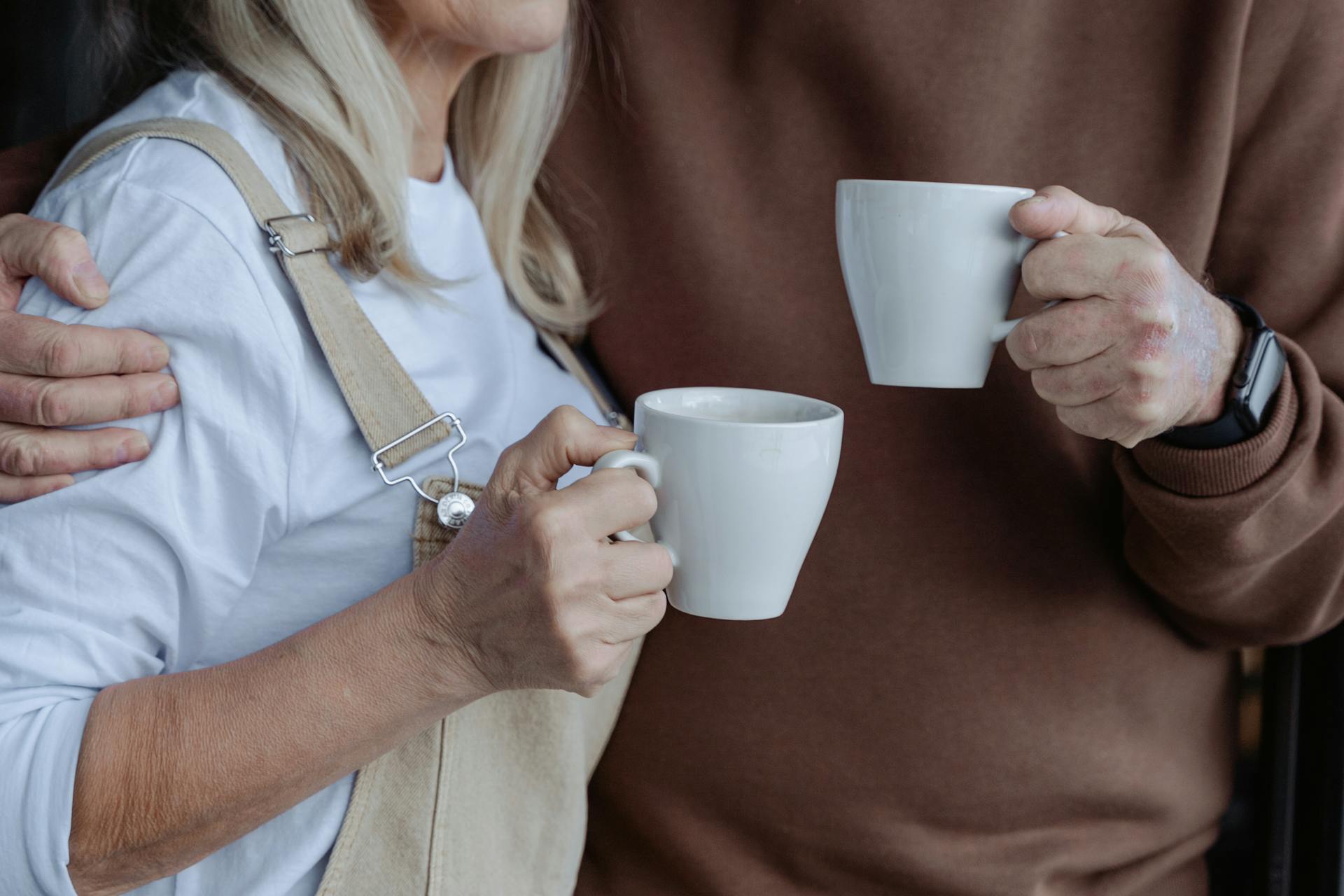 A close-up shot of a couple holding white mugs | Source: Pexels