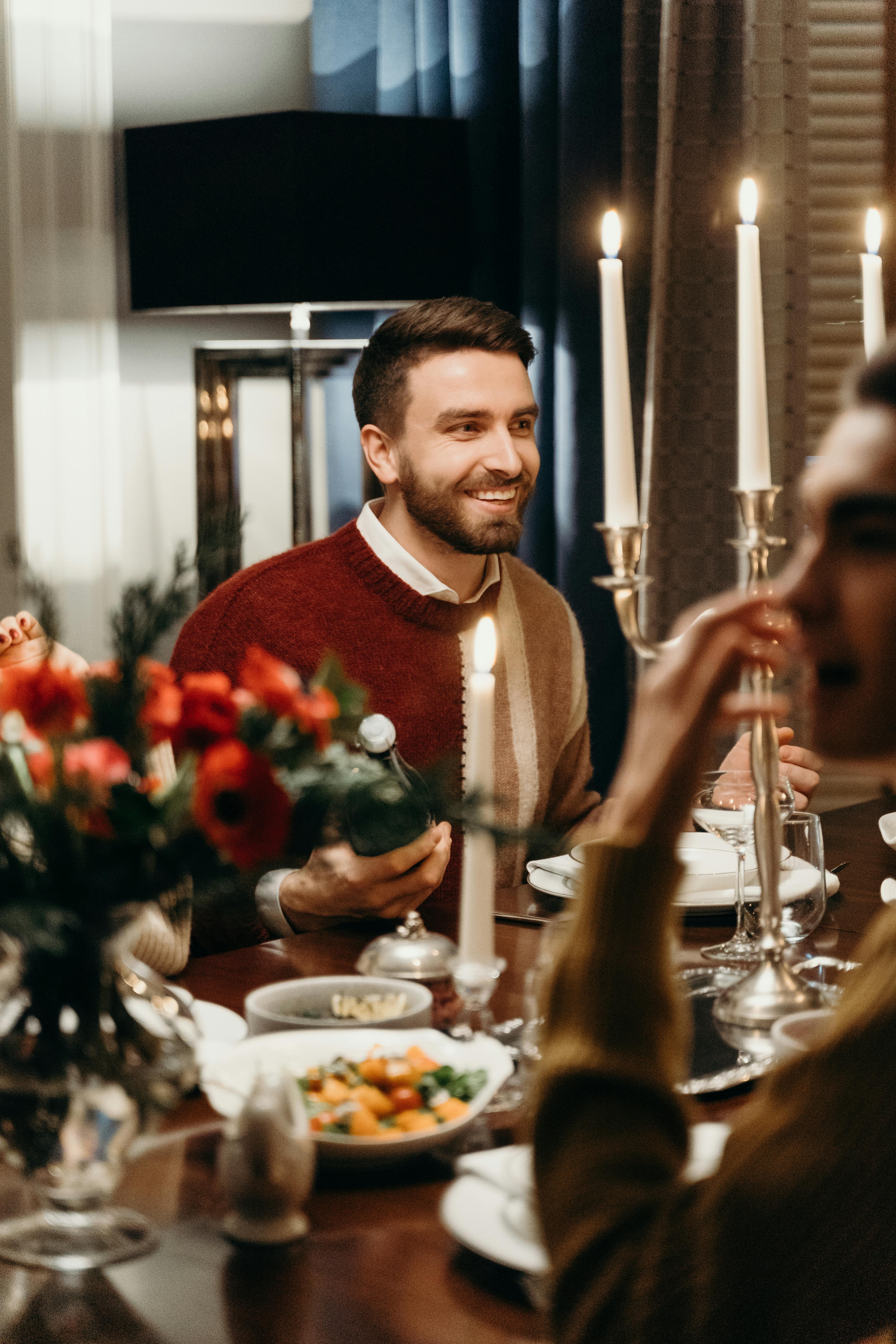 A smiling man at dinner table | Source: Pexels