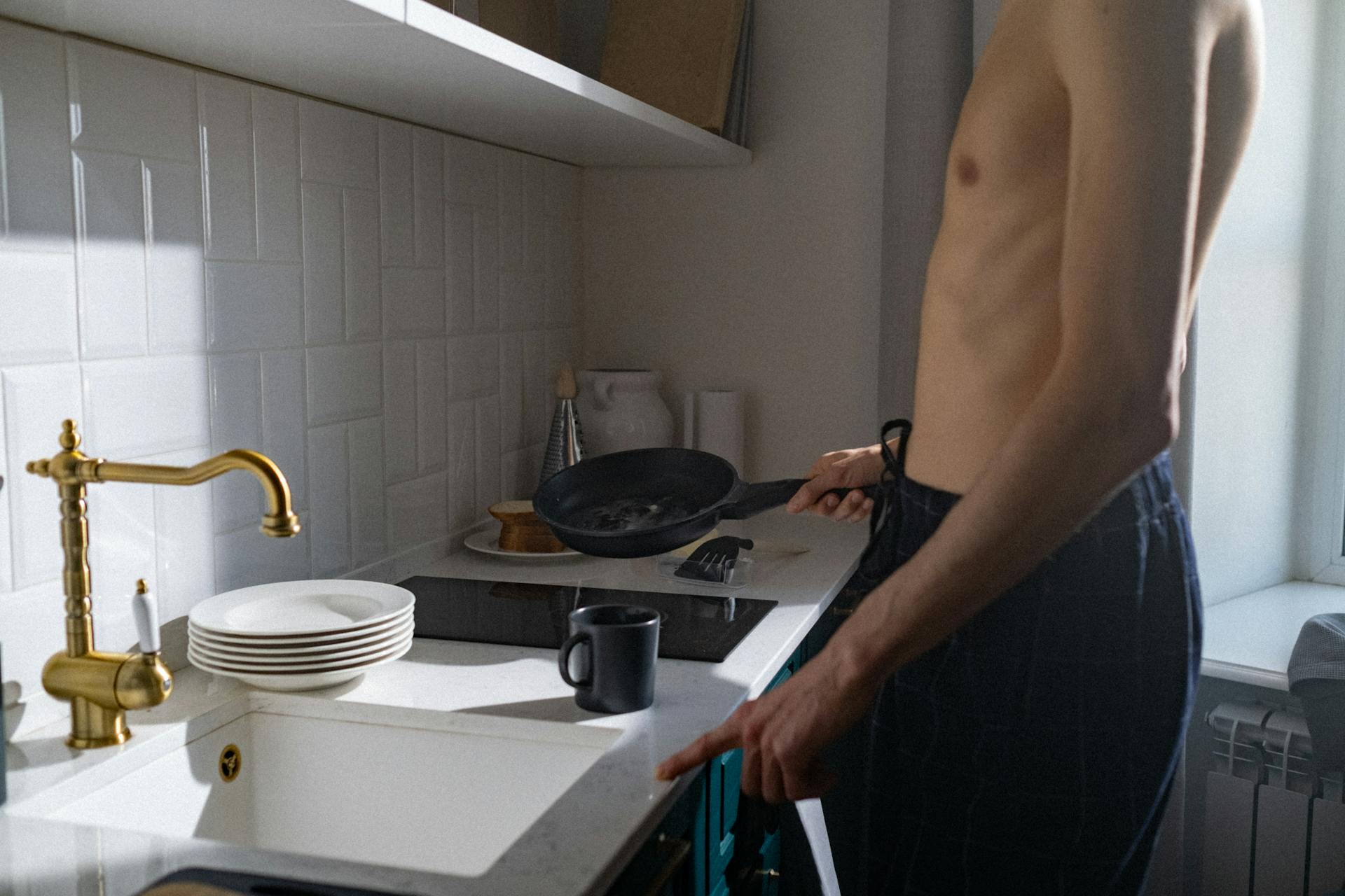 A shirtless man standing near a kitchen sink | Source: Pexels