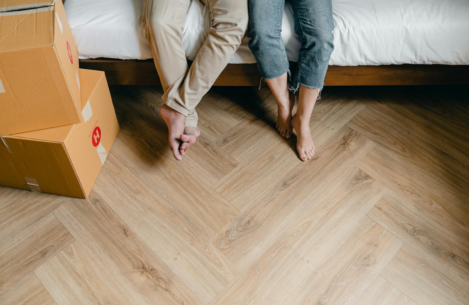 A close-up shot of a couple sitting on the bed with carton boxes around them | Source: Pexels
