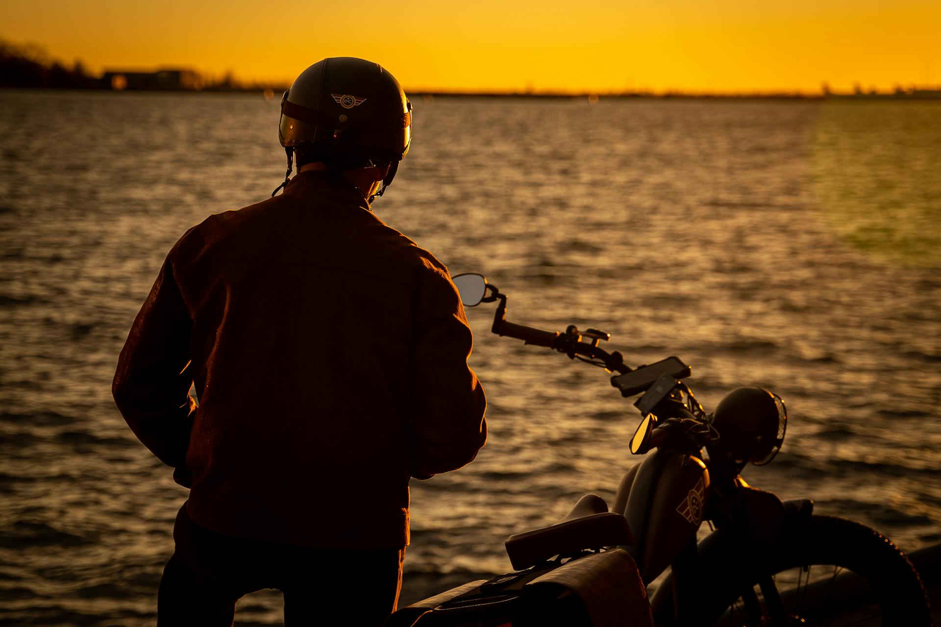 Silhouette of a man standing on the shore near his bike | Source: Pexels