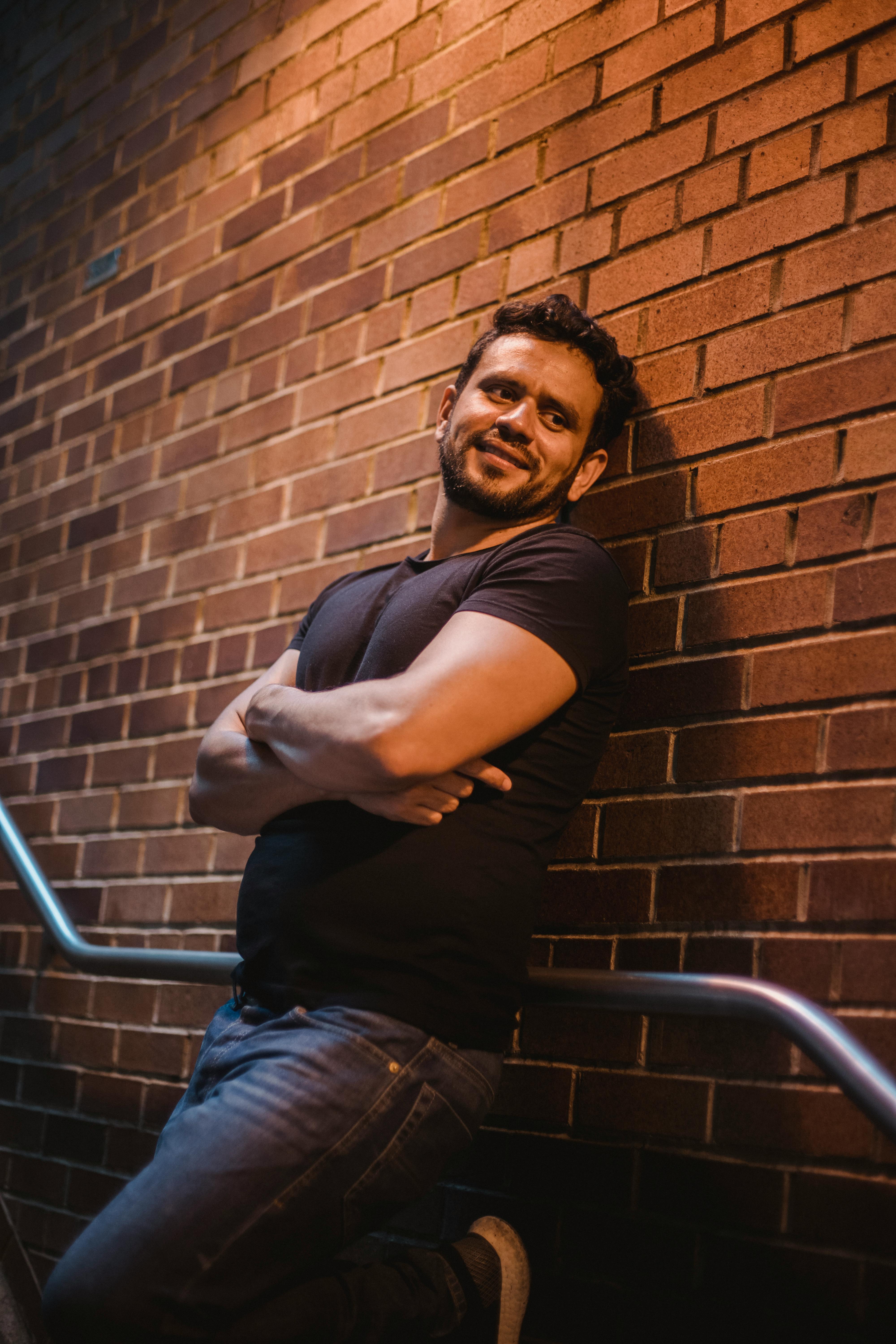 A man smiling slightly while leaning on a wall | Source: Pexels