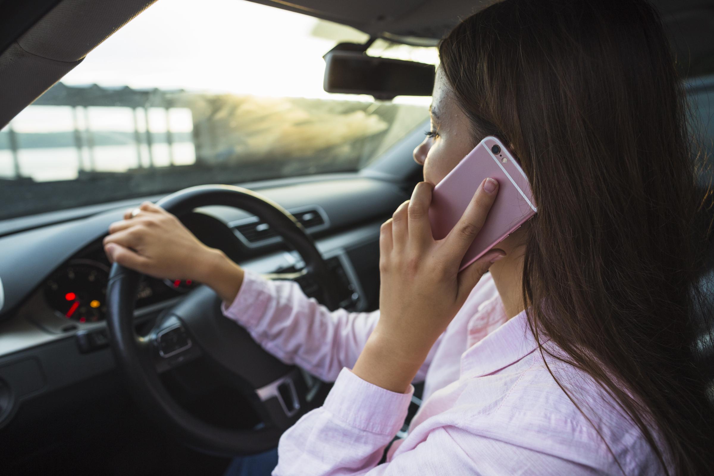 A woman sitting in her car and talking on the phone | Source: Freepik