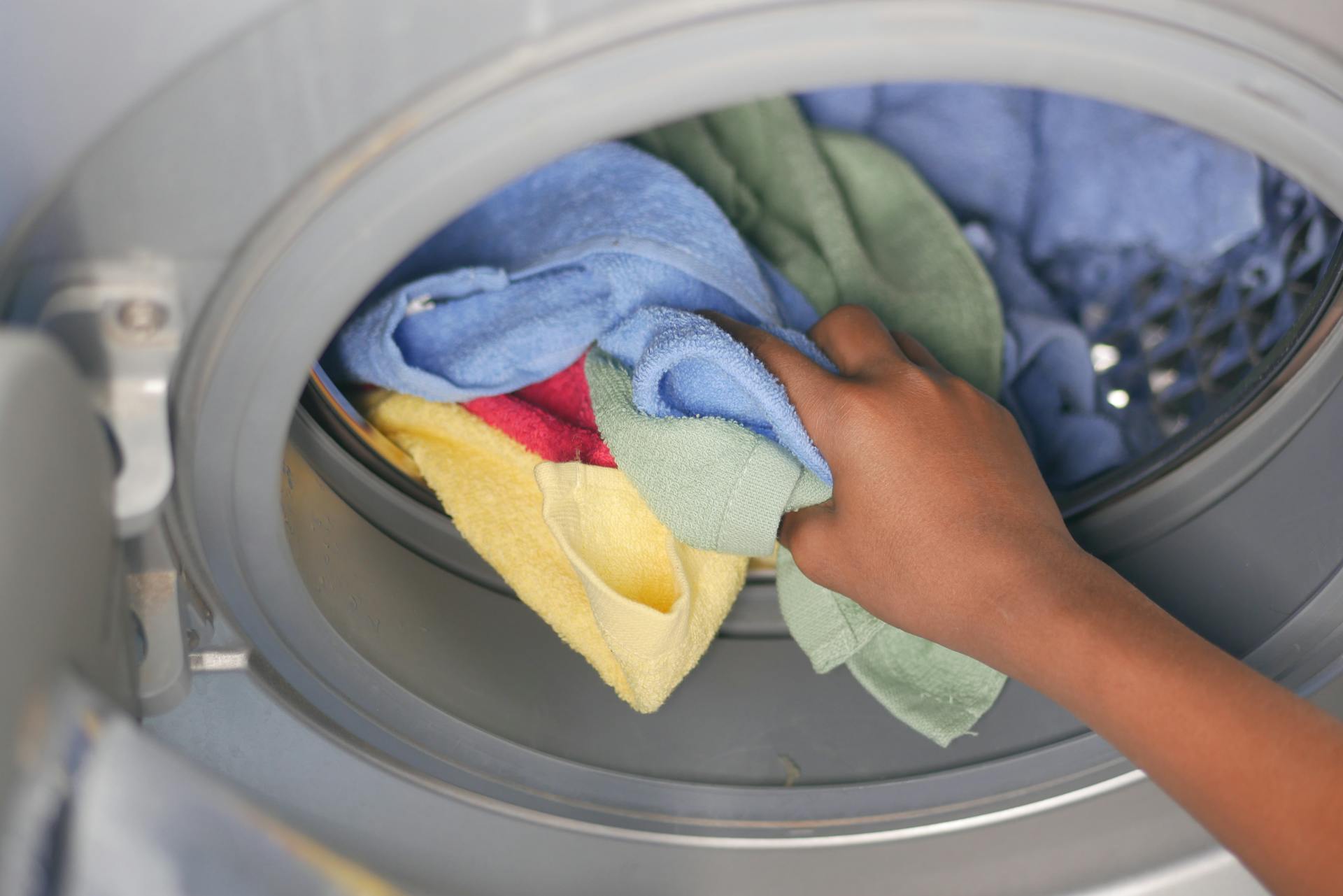 A person putting towels in a washing machine | Source: Pexels