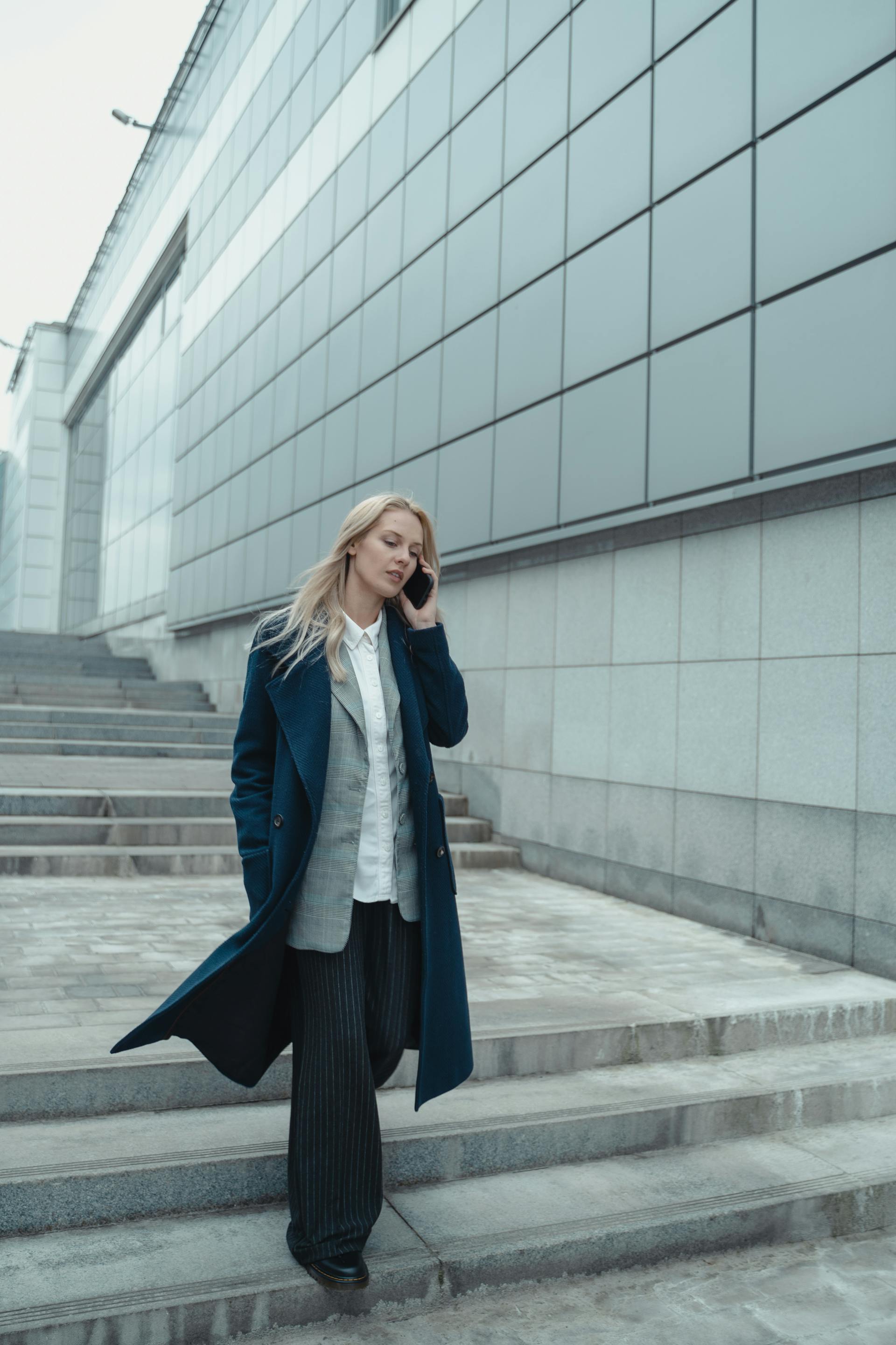 A woman talking on the phone while walking down a staircase | Source: Pexels