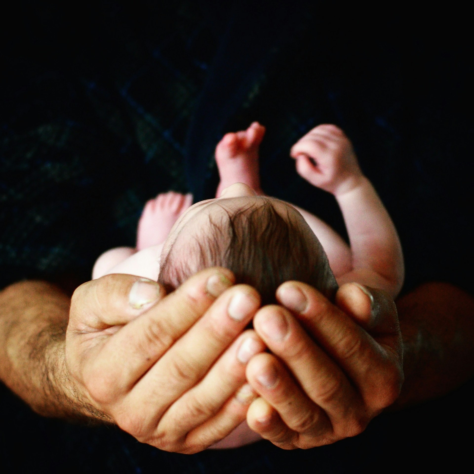 Cropped shot of a man holding a newborn baby | Source: Unsplash