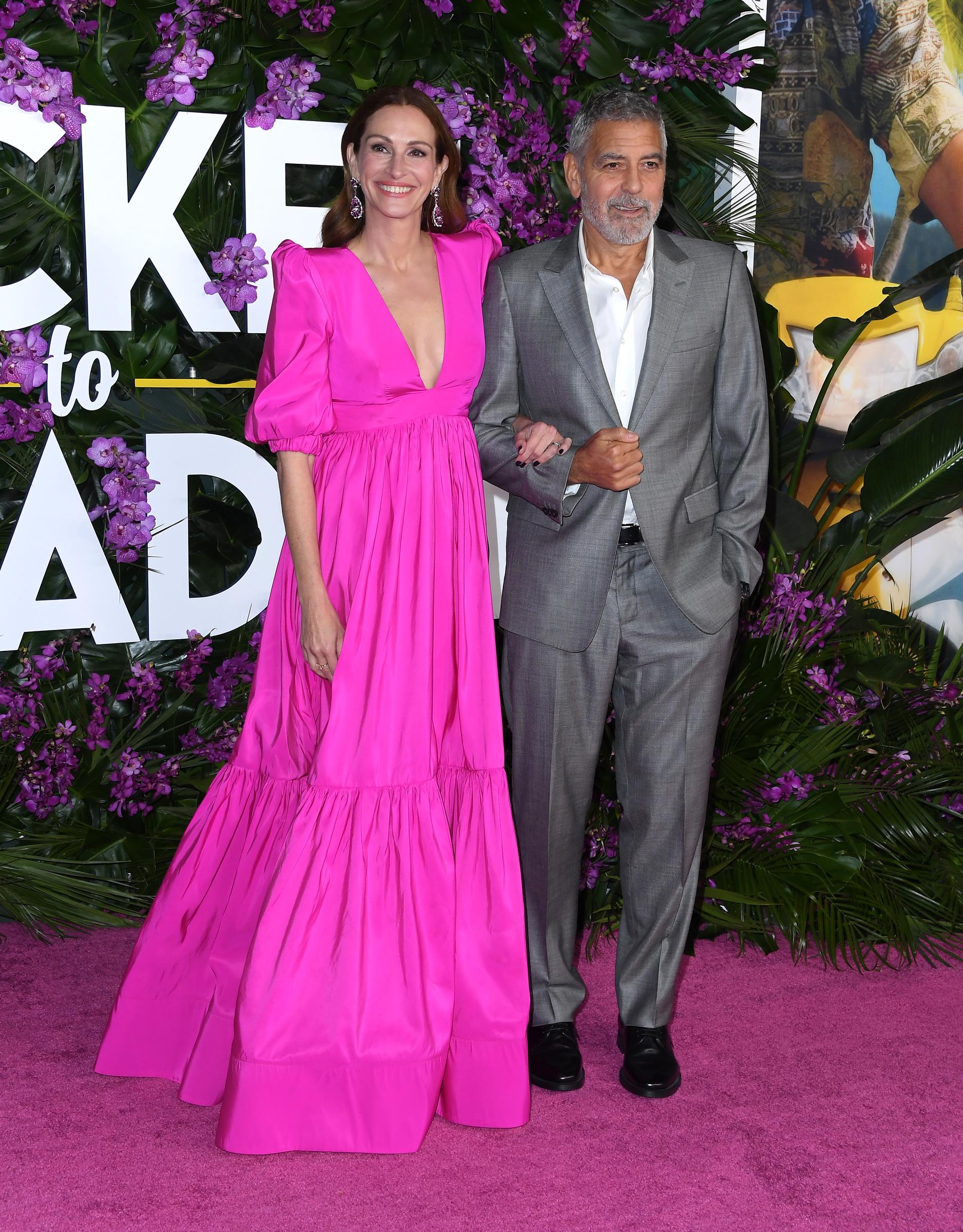 Julia Roberts and George Clooney arrive at the premiere of Universal Pictures’ "Ticket to Paradise" at the Regency Village Theatre on October 17, 2022, in Los Angeles, California. Roberts wears a hot pink dress, complementing Clooney’s gray suit.
