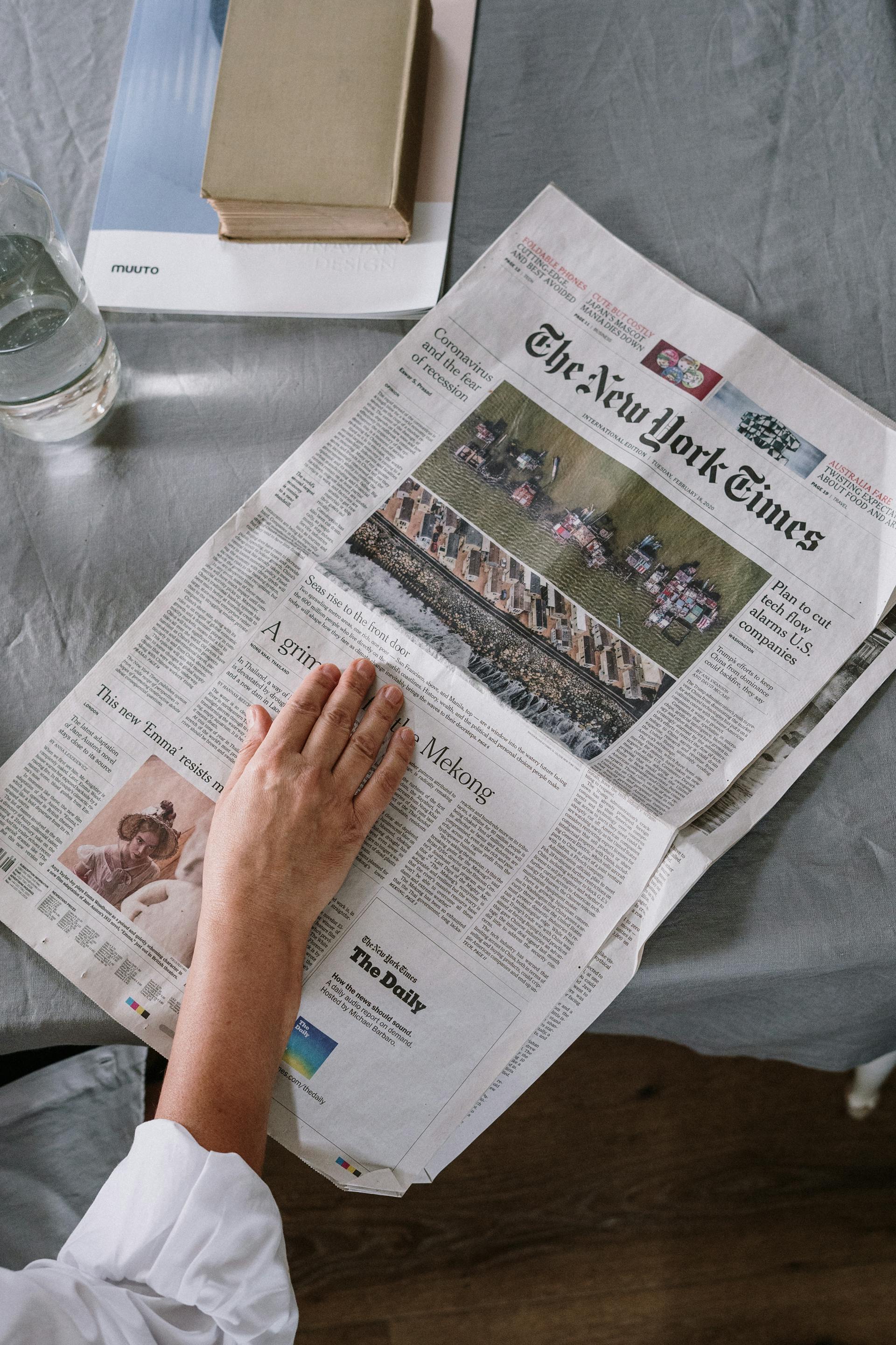 A close-up shot of a person's hand resting on a newspaper | Source: Pexels