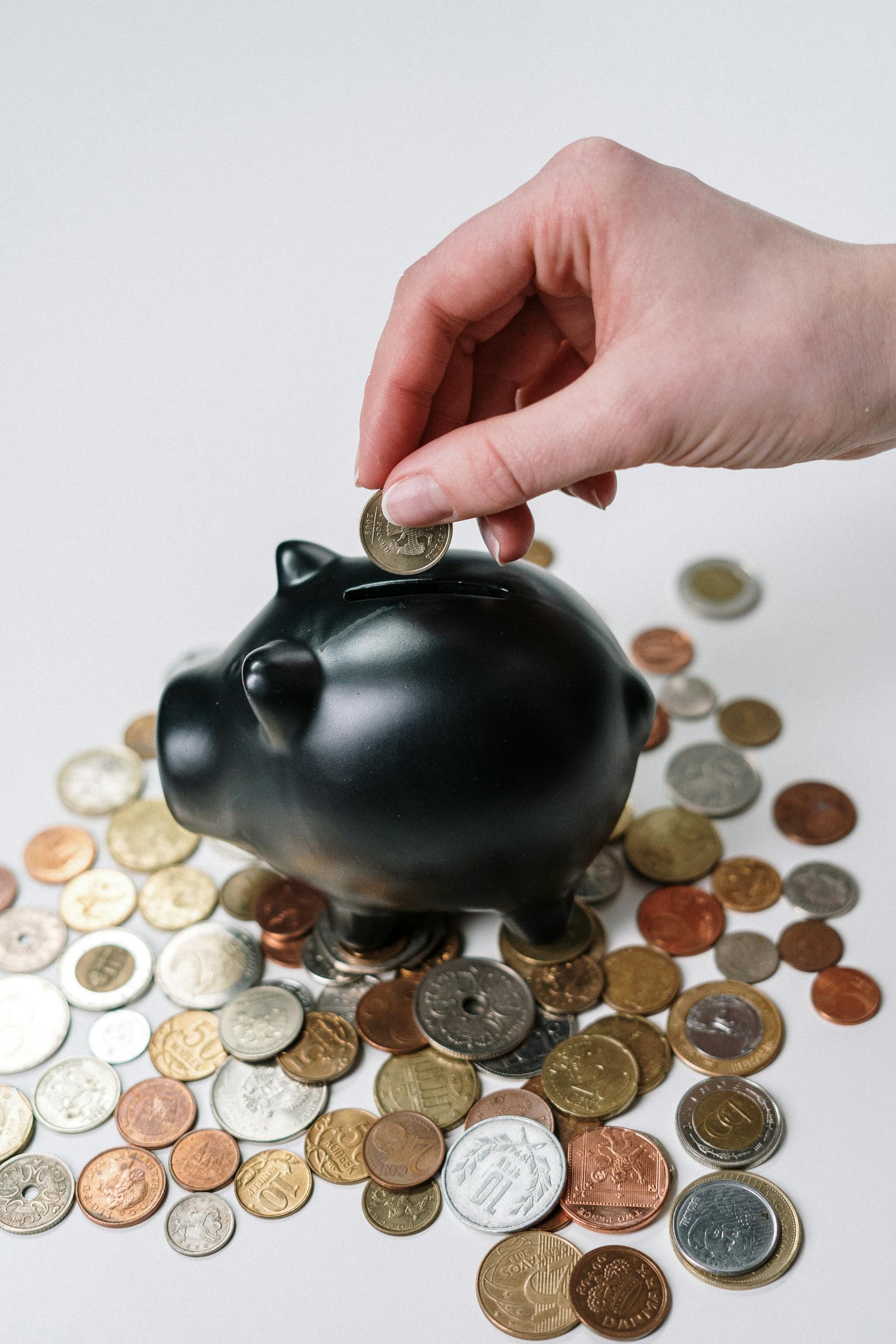 A woman putting a coin in a piggy bank | Source: Pexels