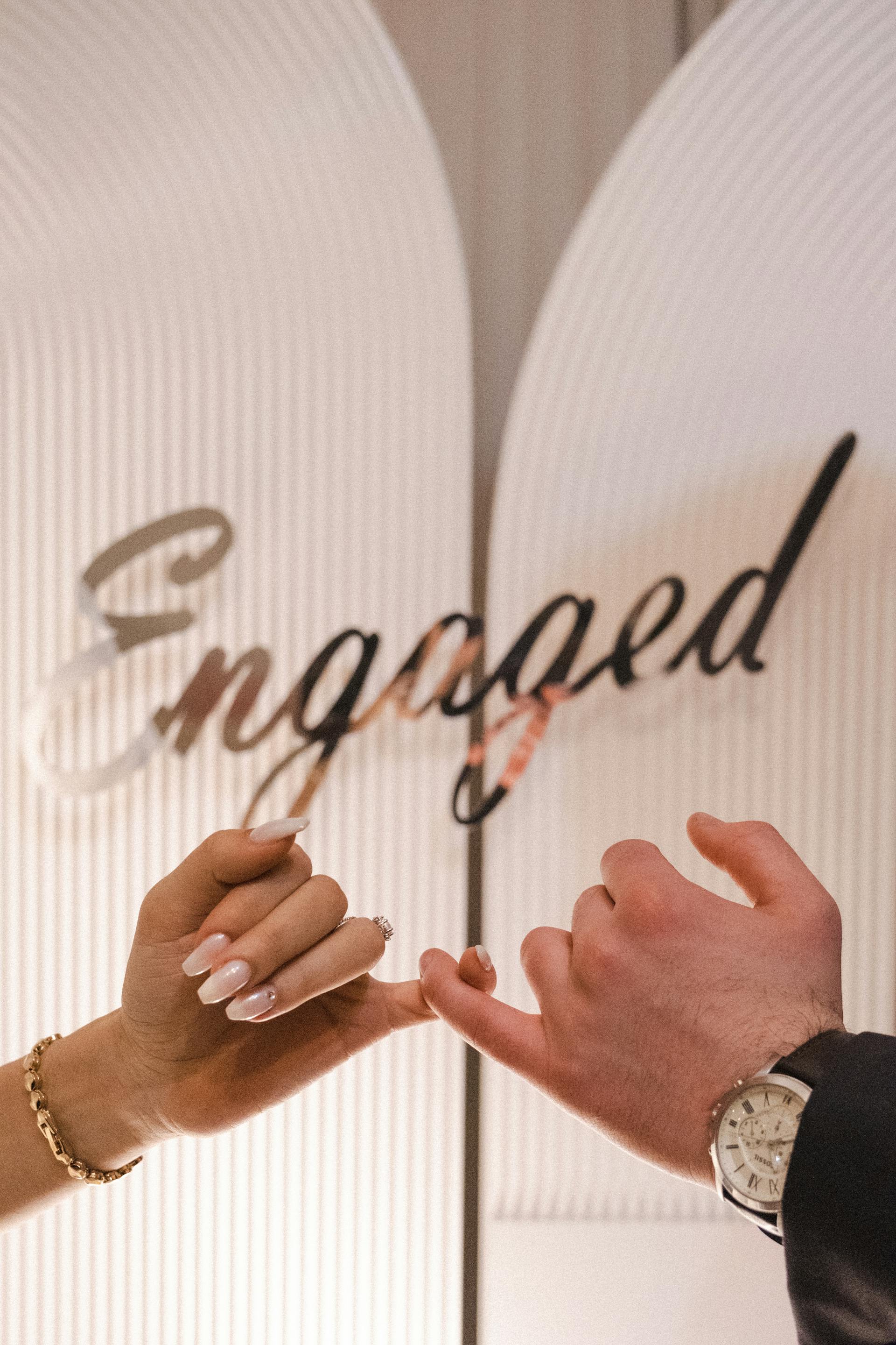 A couple holding their pinky fingers together at their engagement party | Source: Pexels