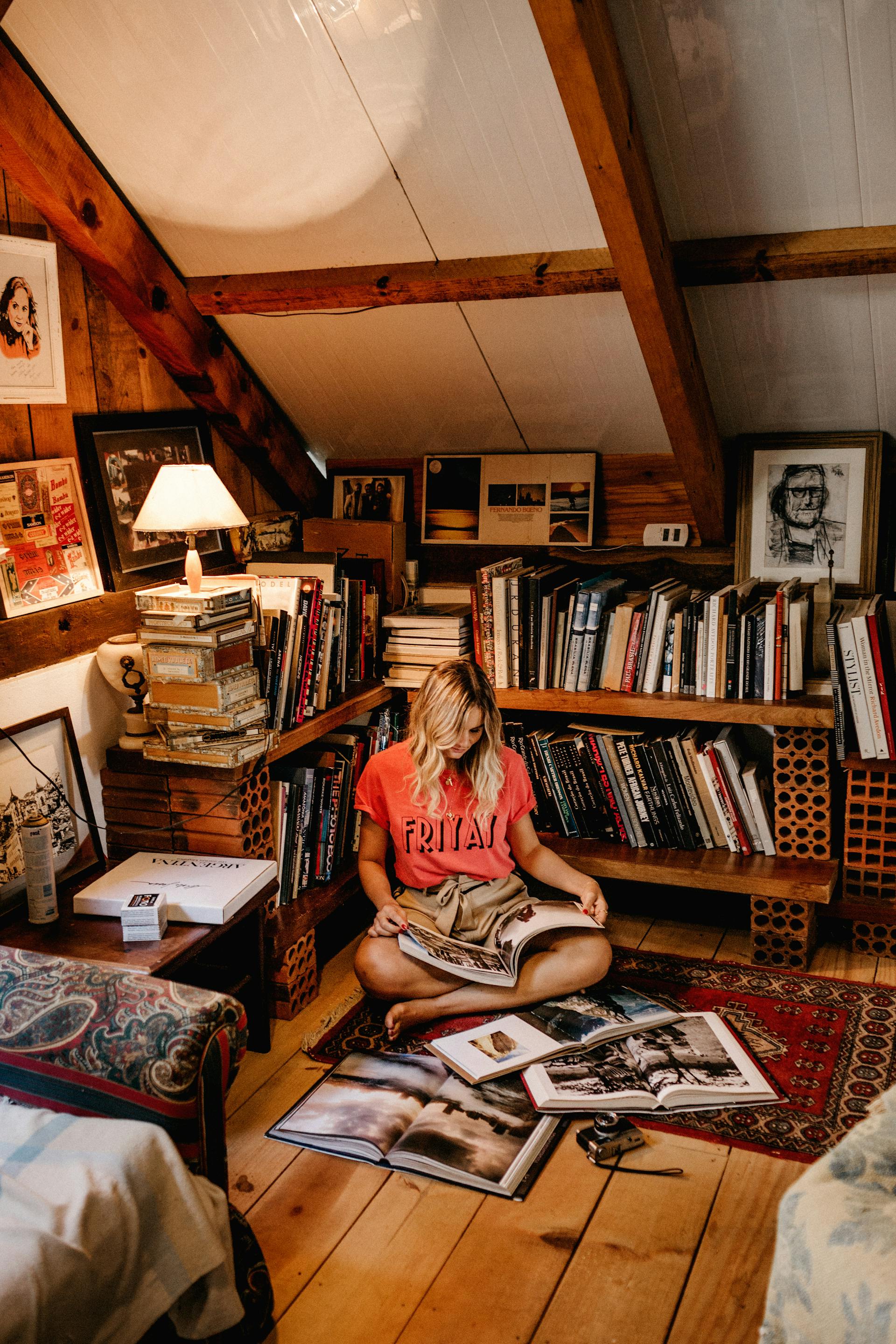 A woman reading a book while sitting on the floor in her home library | Source: Pexels