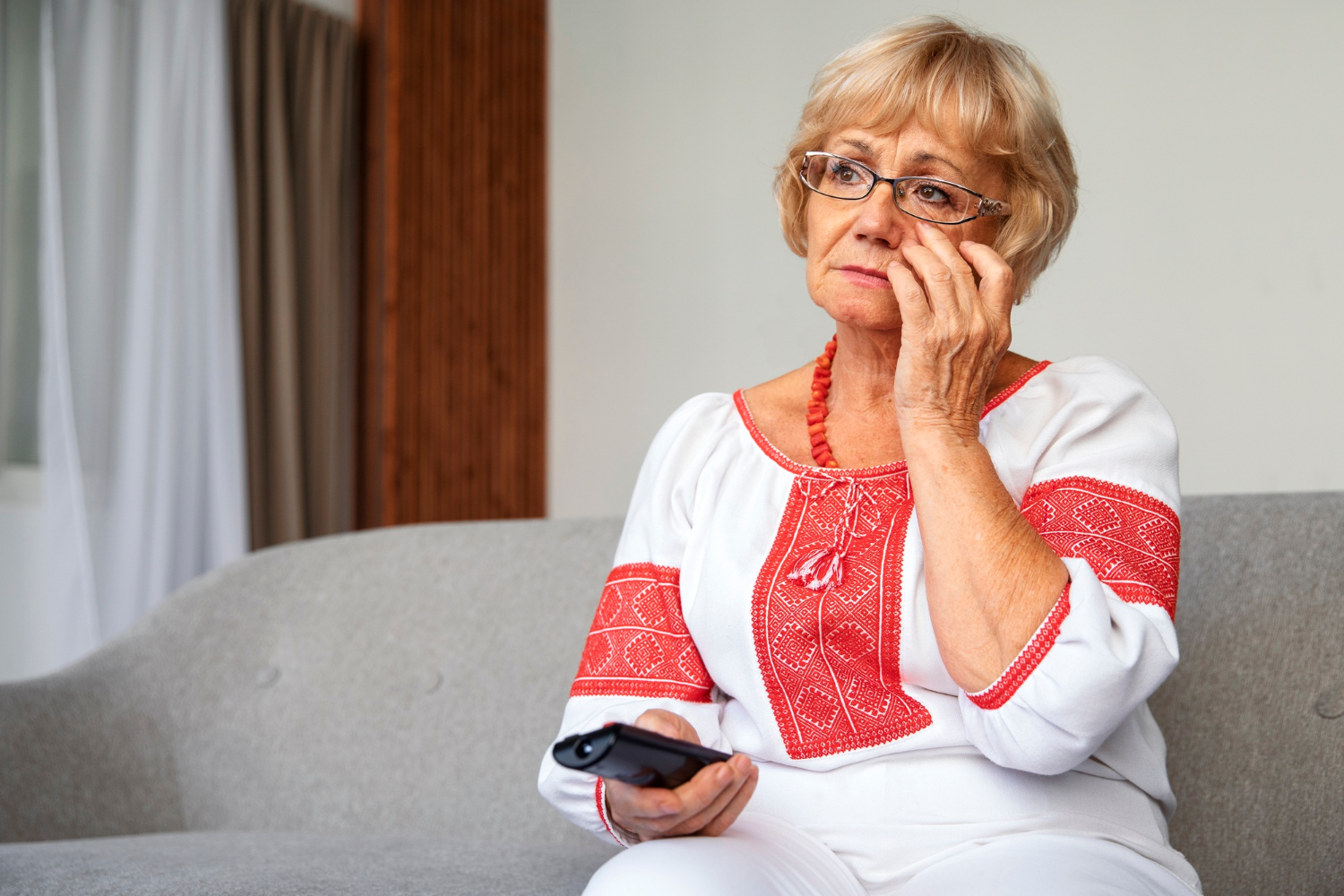 A sad senior woman holding a TV remote | Source: Freepik