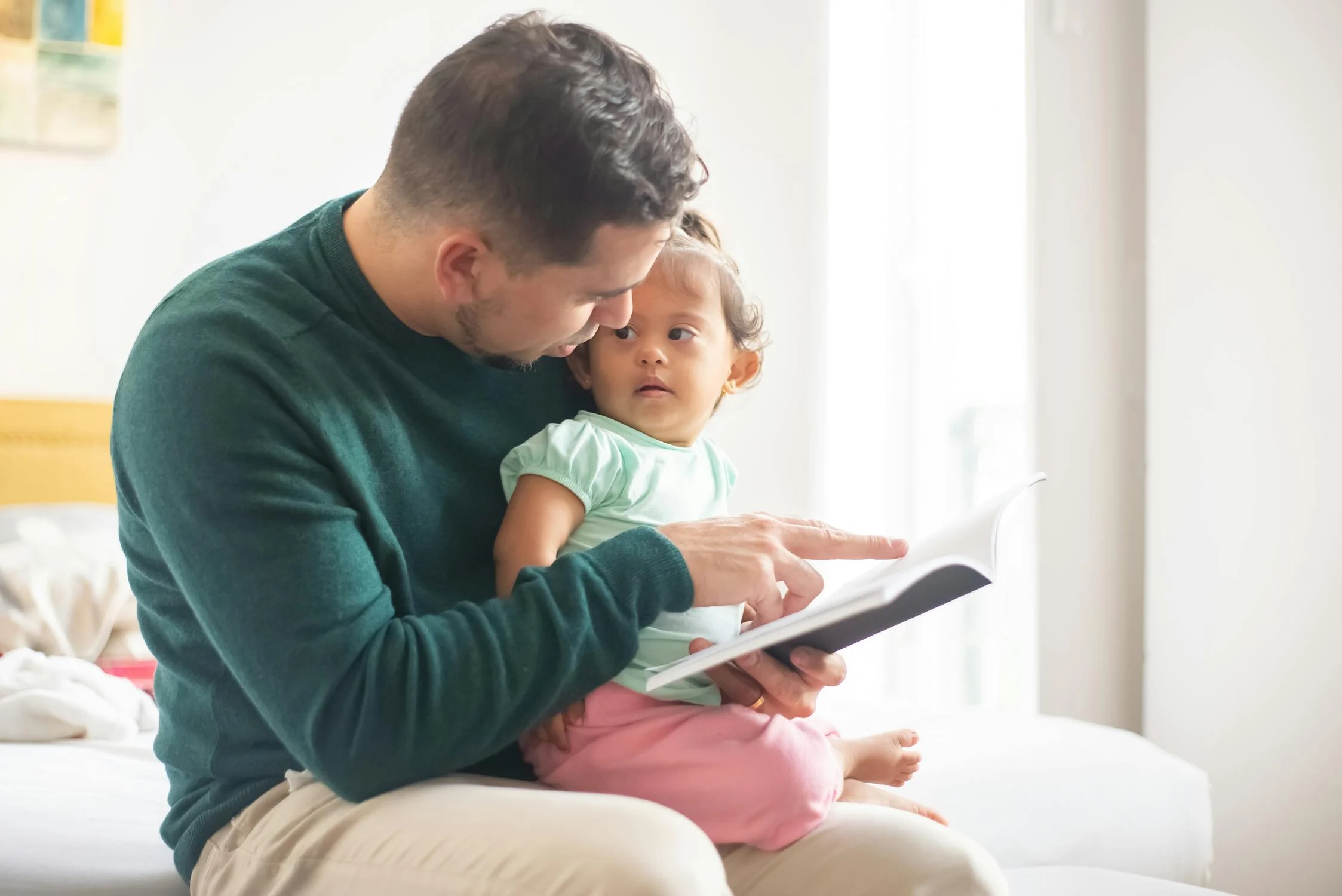 A man reading a book to his daughter | Source: Pexels