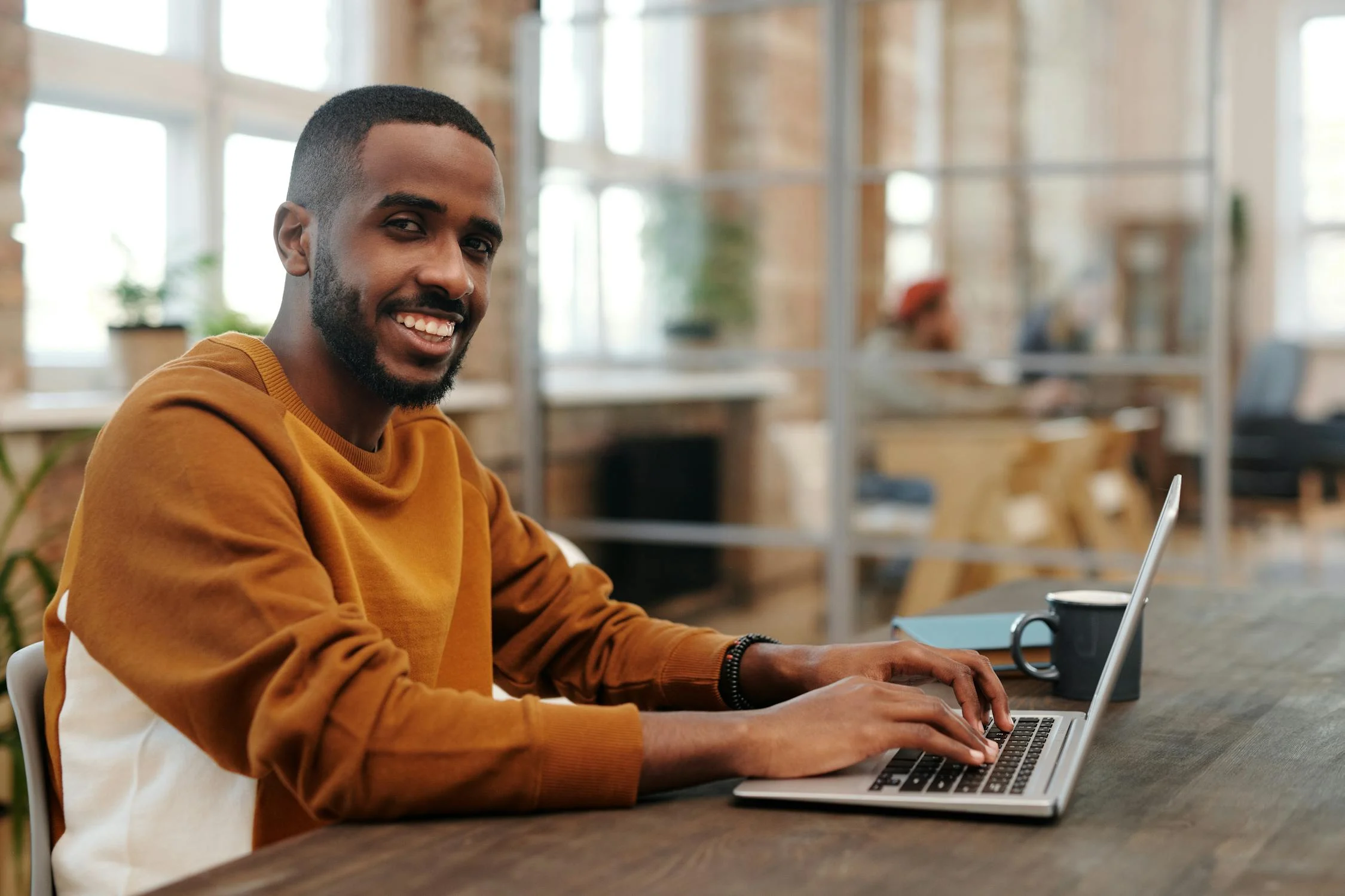 Un hombre sonriente con una computadora portátil | Fuente: Pexels