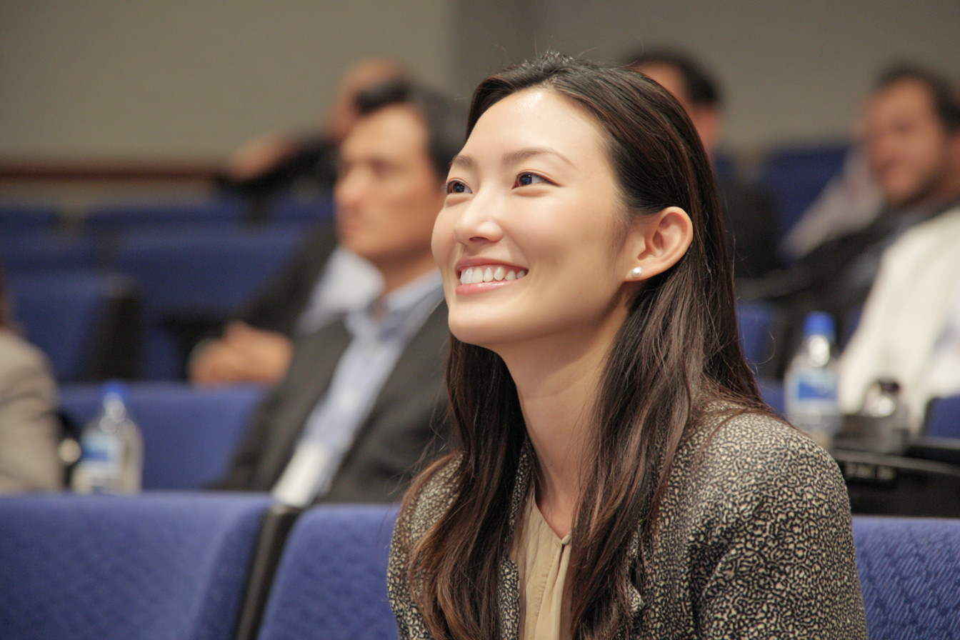 A woman in an auditorium smiling | Source: Midjourney