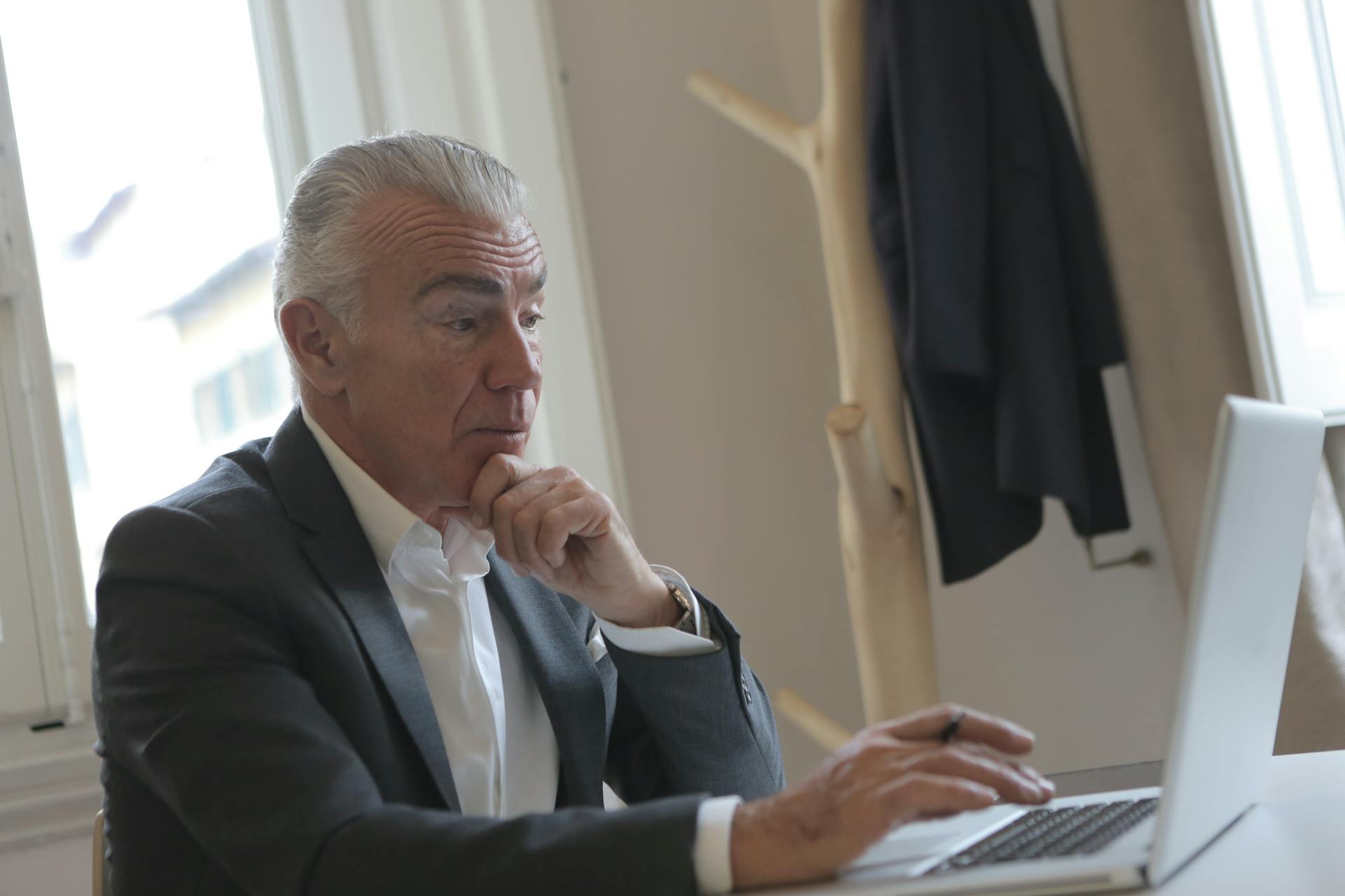 An elegant older man using his laptop in his office | Source: Pexels