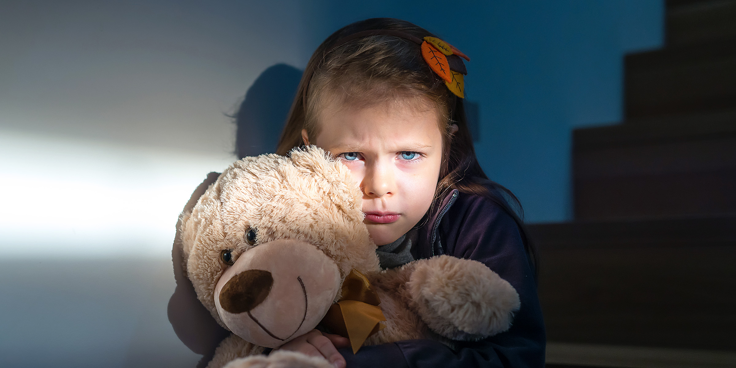 A sad and scared little girl clutching a teddy bear | Source: Shutterstock