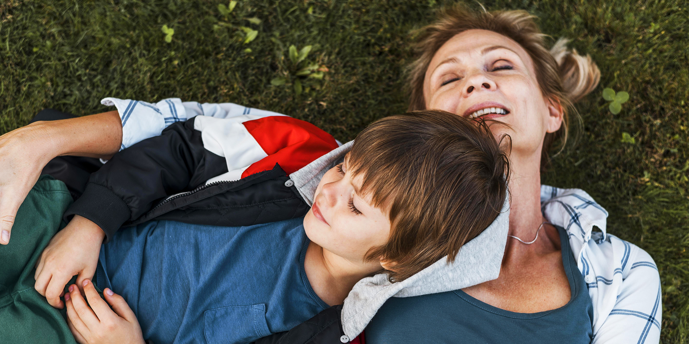 A woman lying on a lawn with her son | Source: freepik.com/freepik