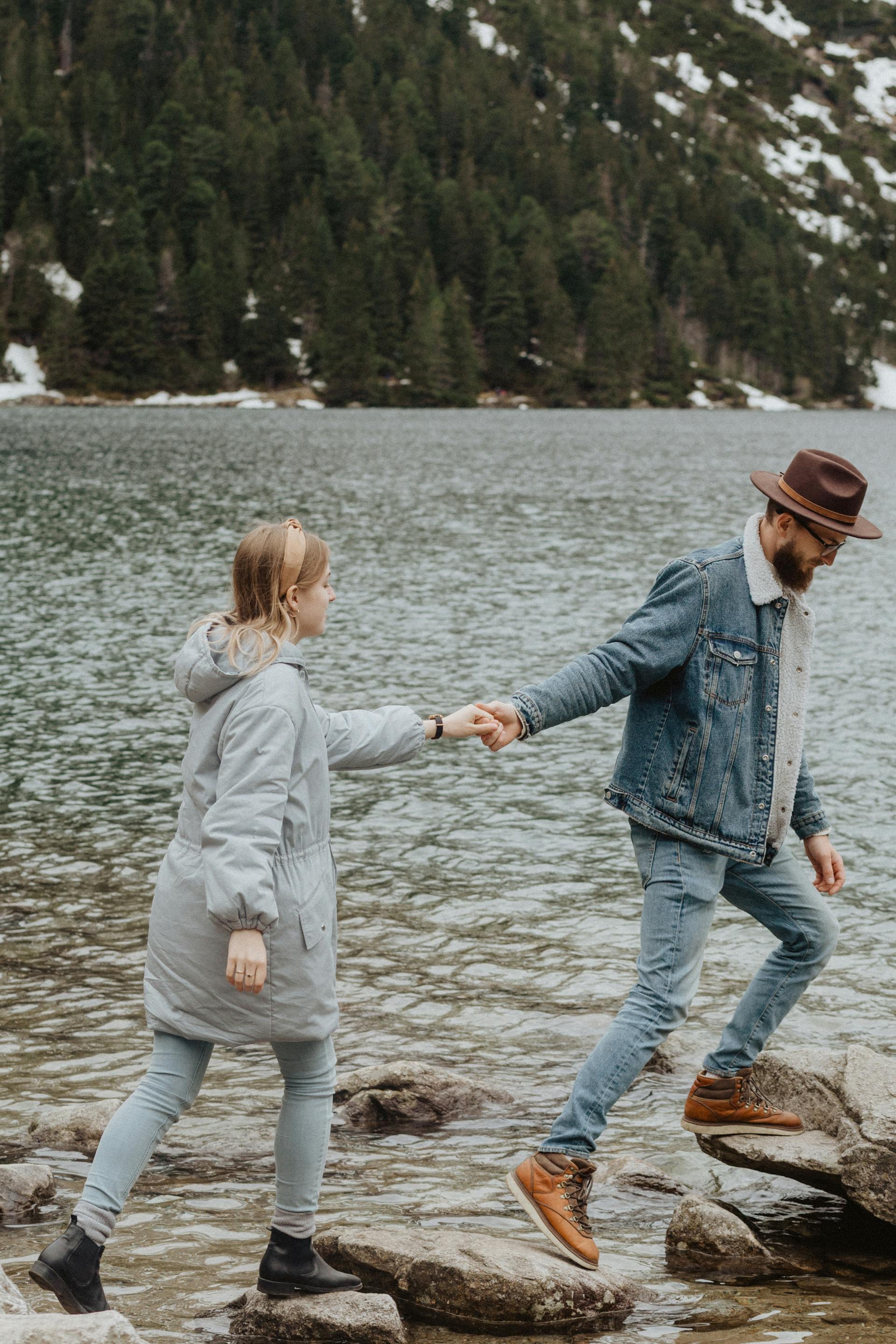 A couple walking on rocks near a lake | Source: Pexels