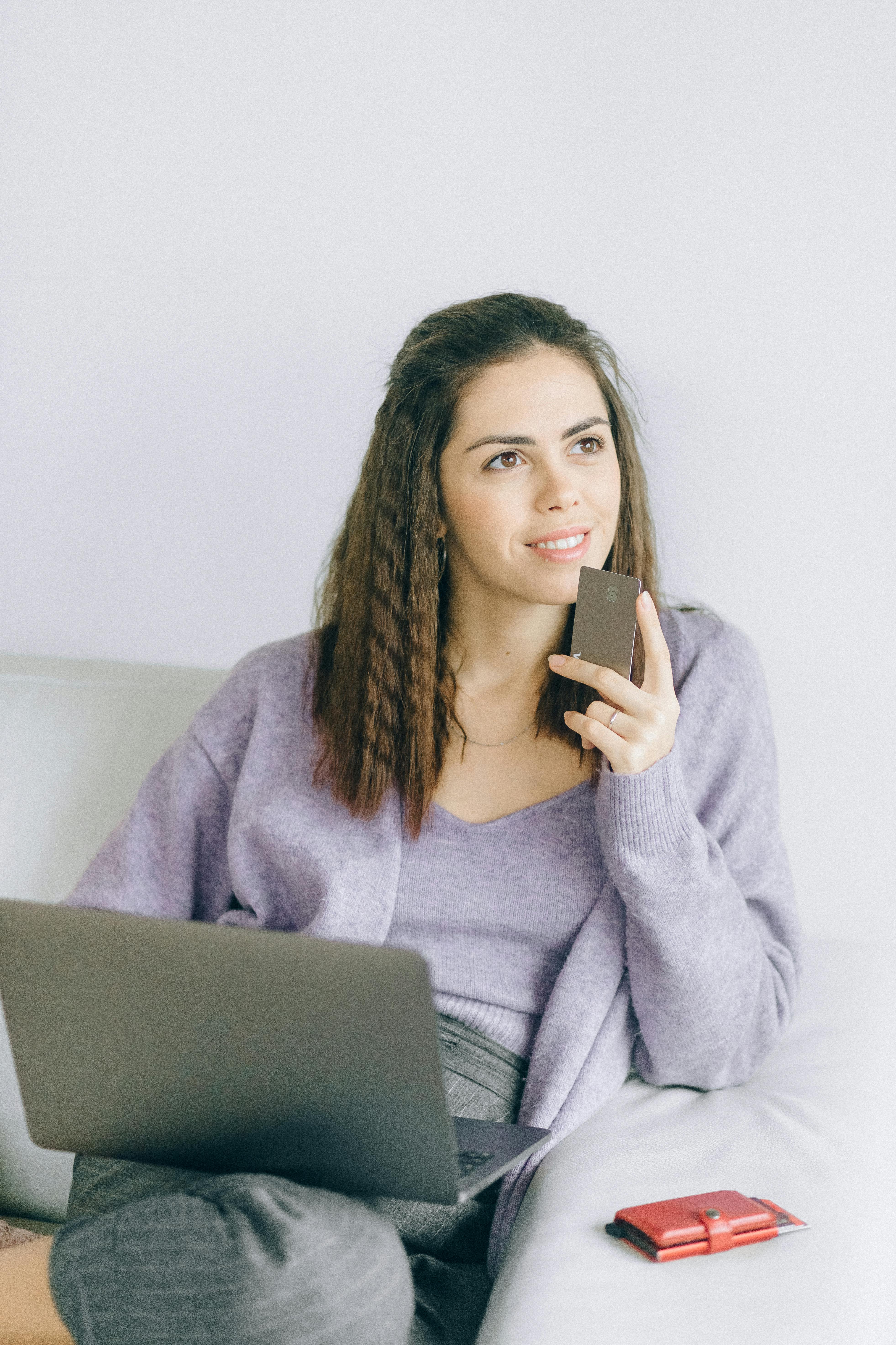 A woman holding a bank card and laptop | Source: Pexels