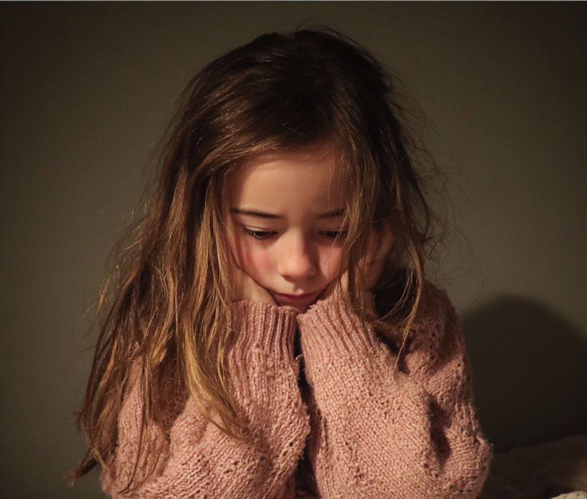 A little girl holding her head | Source: Midjourney