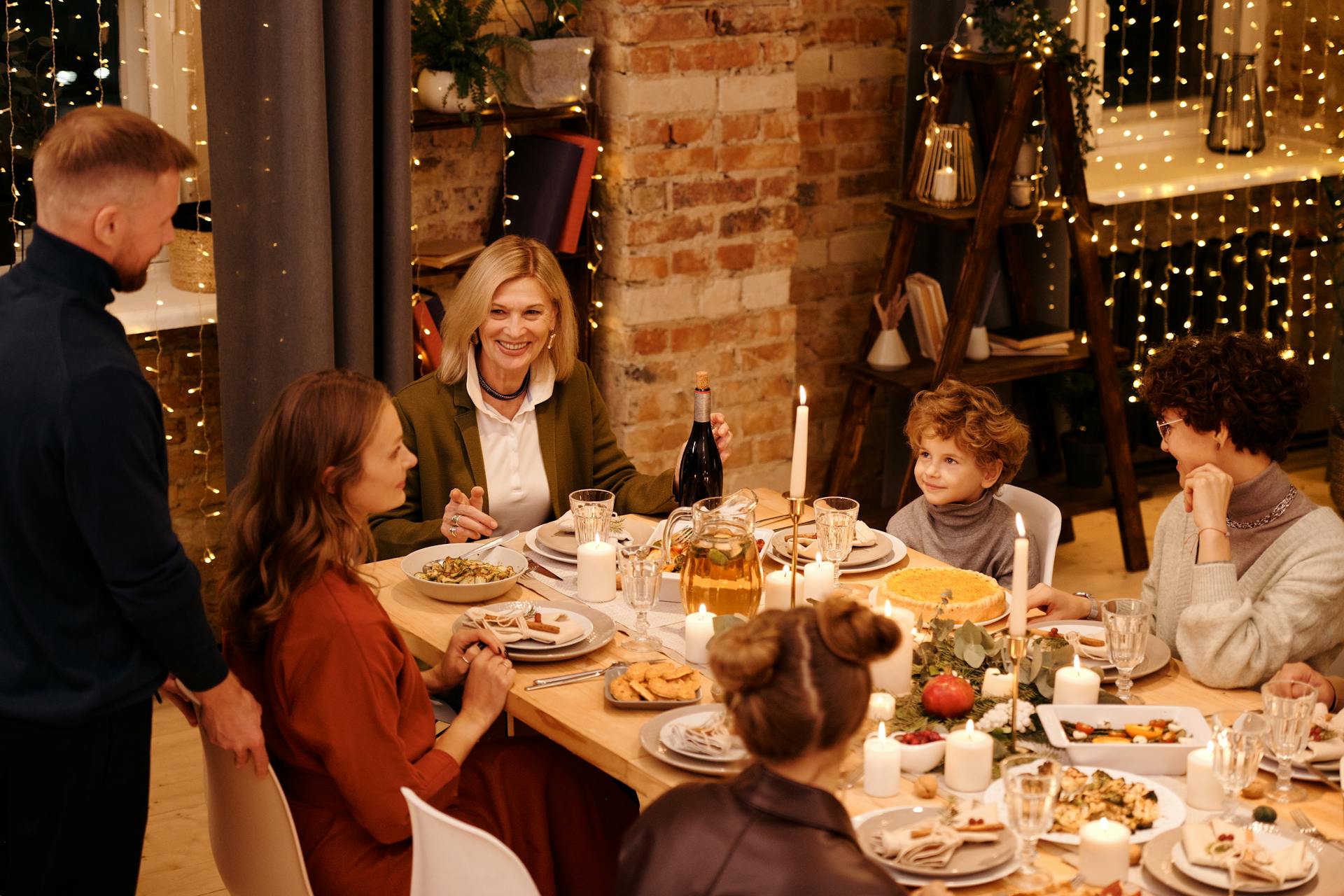 A family sitting around a candlelit table with a holiday feast | Source: Pexels