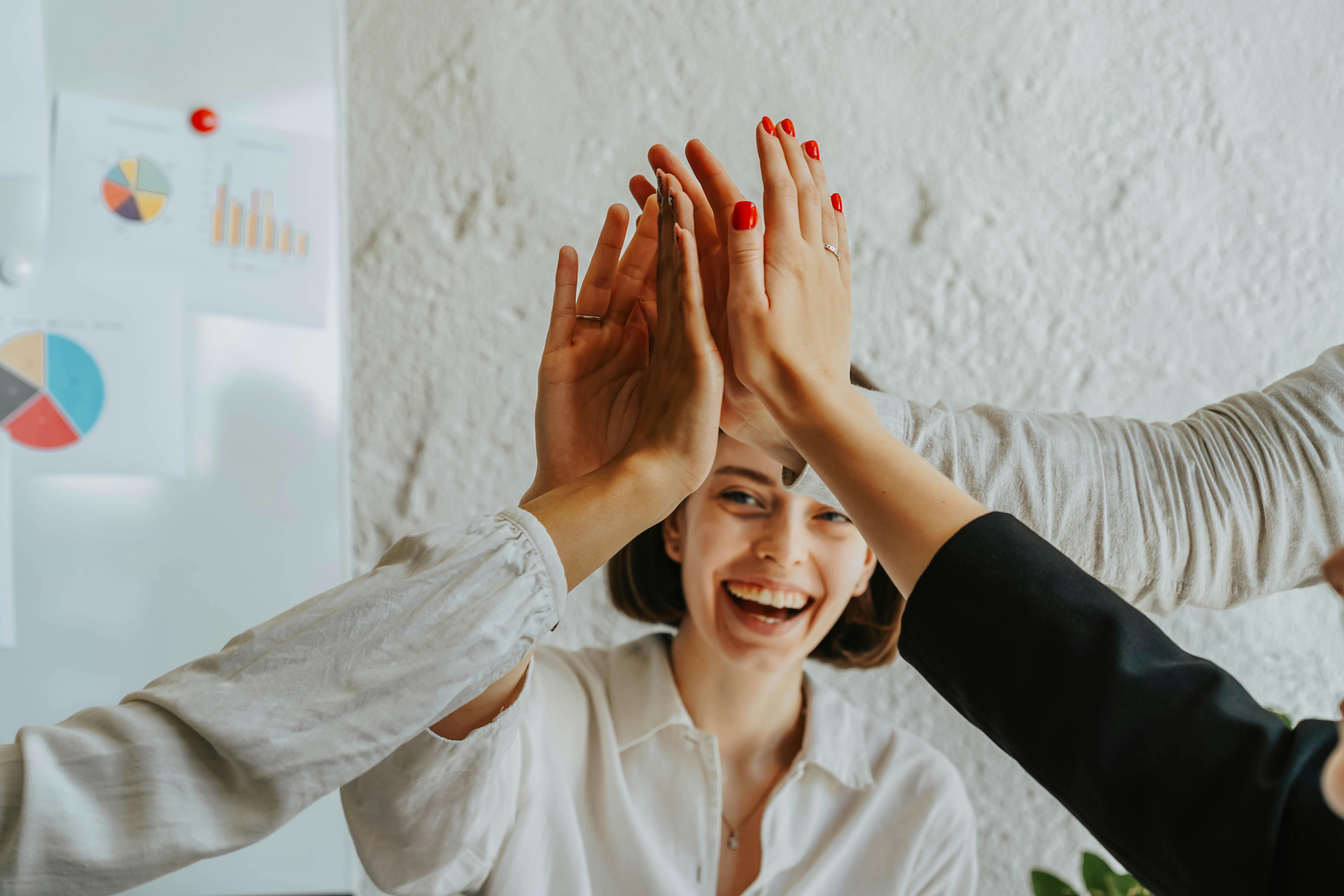 A group of happy people sharing high-fives in an office | Source: Pexels