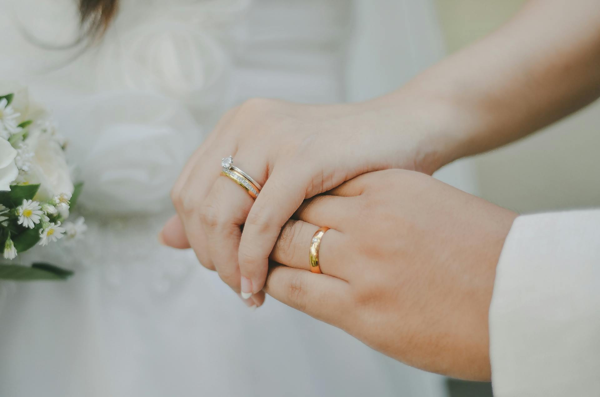 A bride and groom holding hands and showing their wedding rings | Source: Pexels