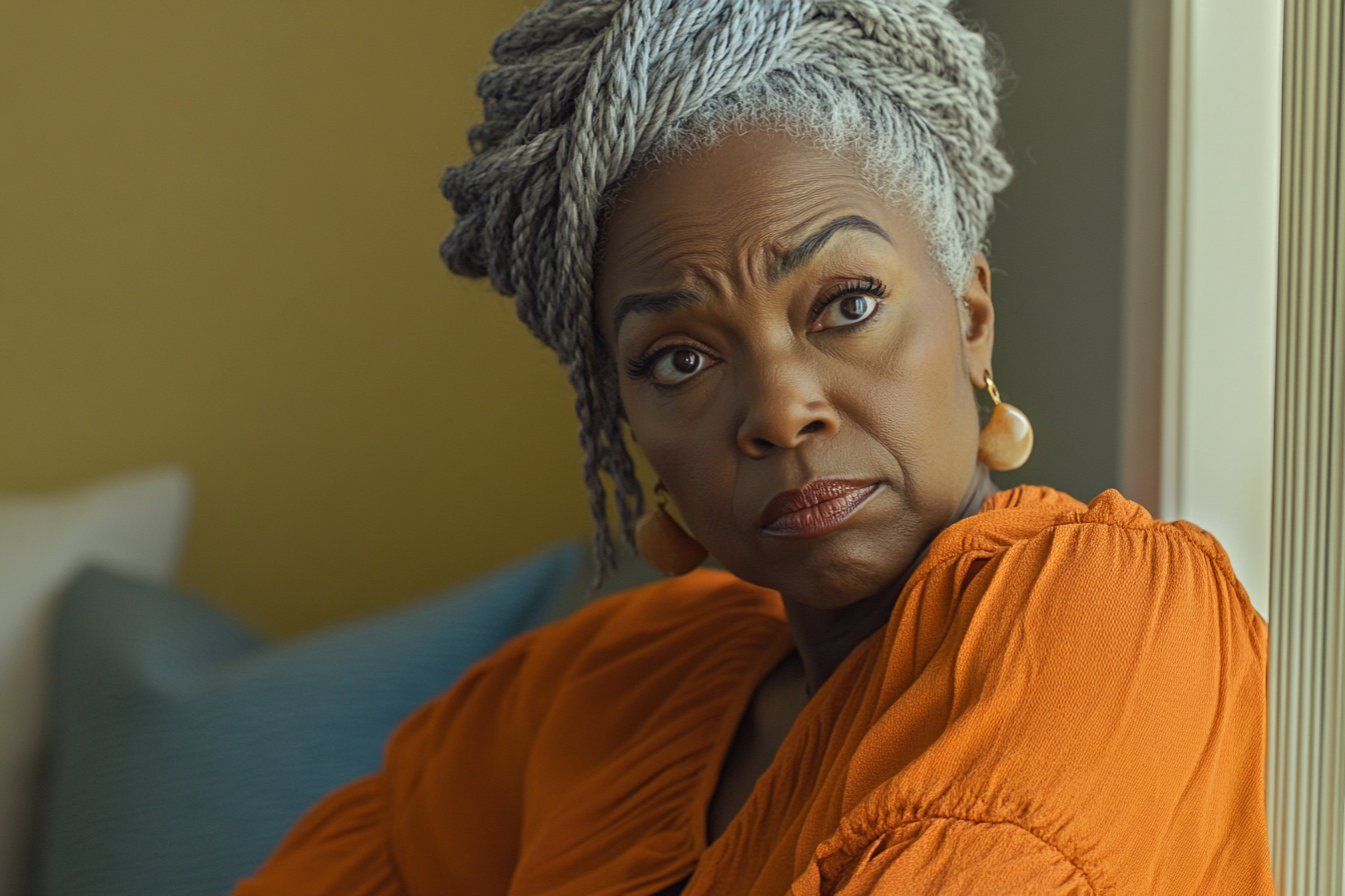 A tight-lipped older woman sitting on a couch and looking to the side | Source: Midjourney