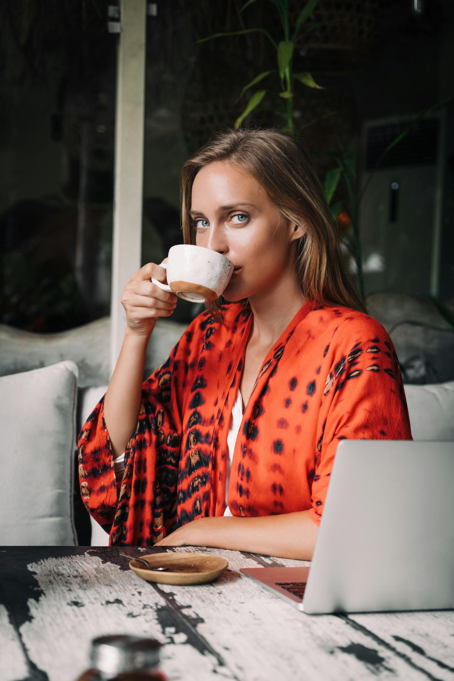 A woman drinking coffee with her laptop in front of her | Source: Pexels