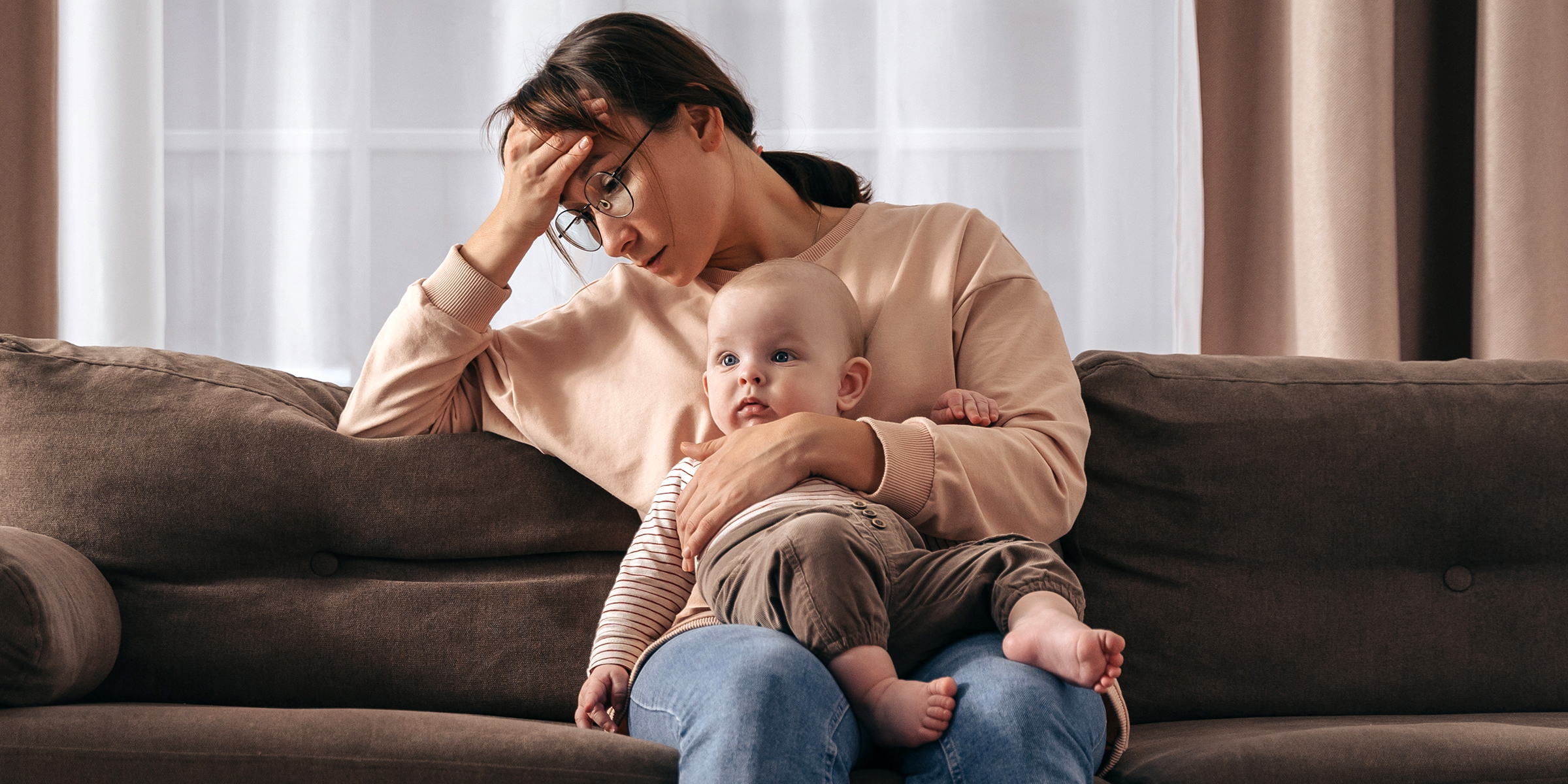 A sad woman with a baby on her lap | Source: Shutterstock