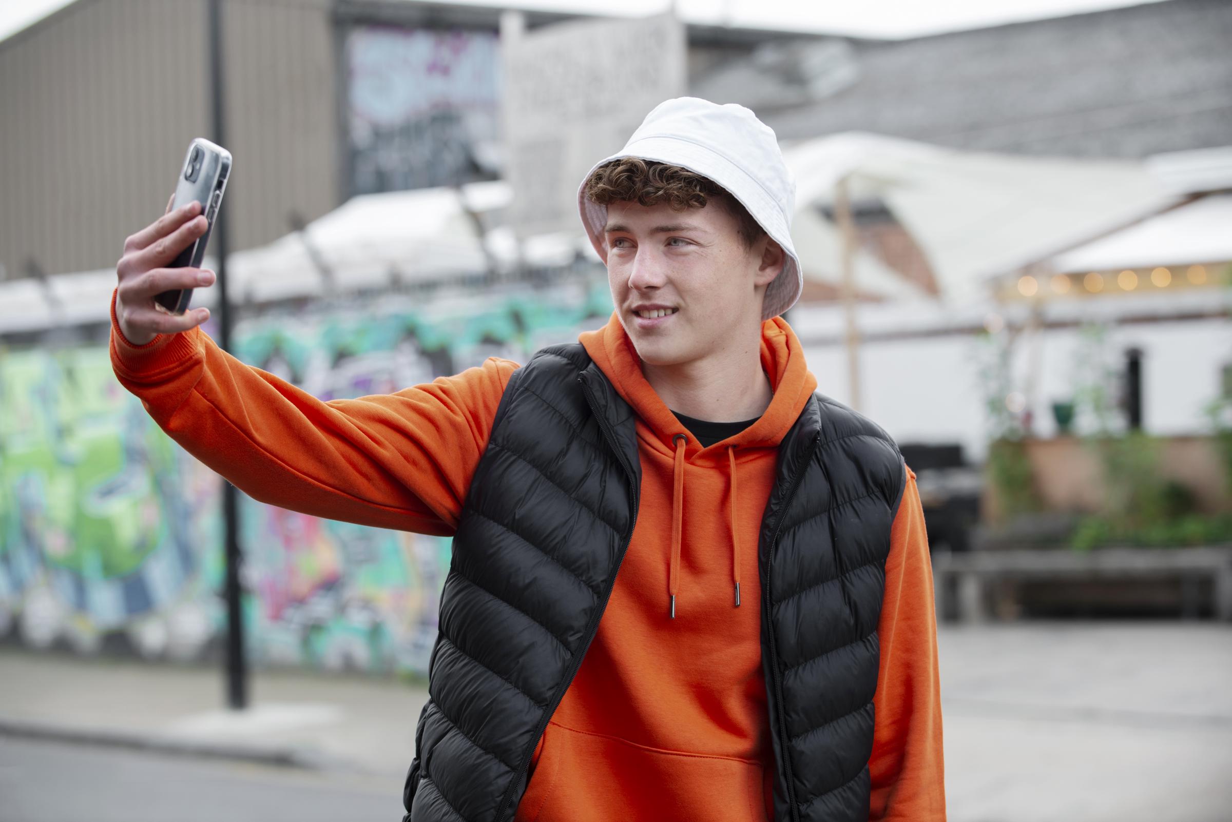 An amused boy recording something with his phone | Source: Freepik