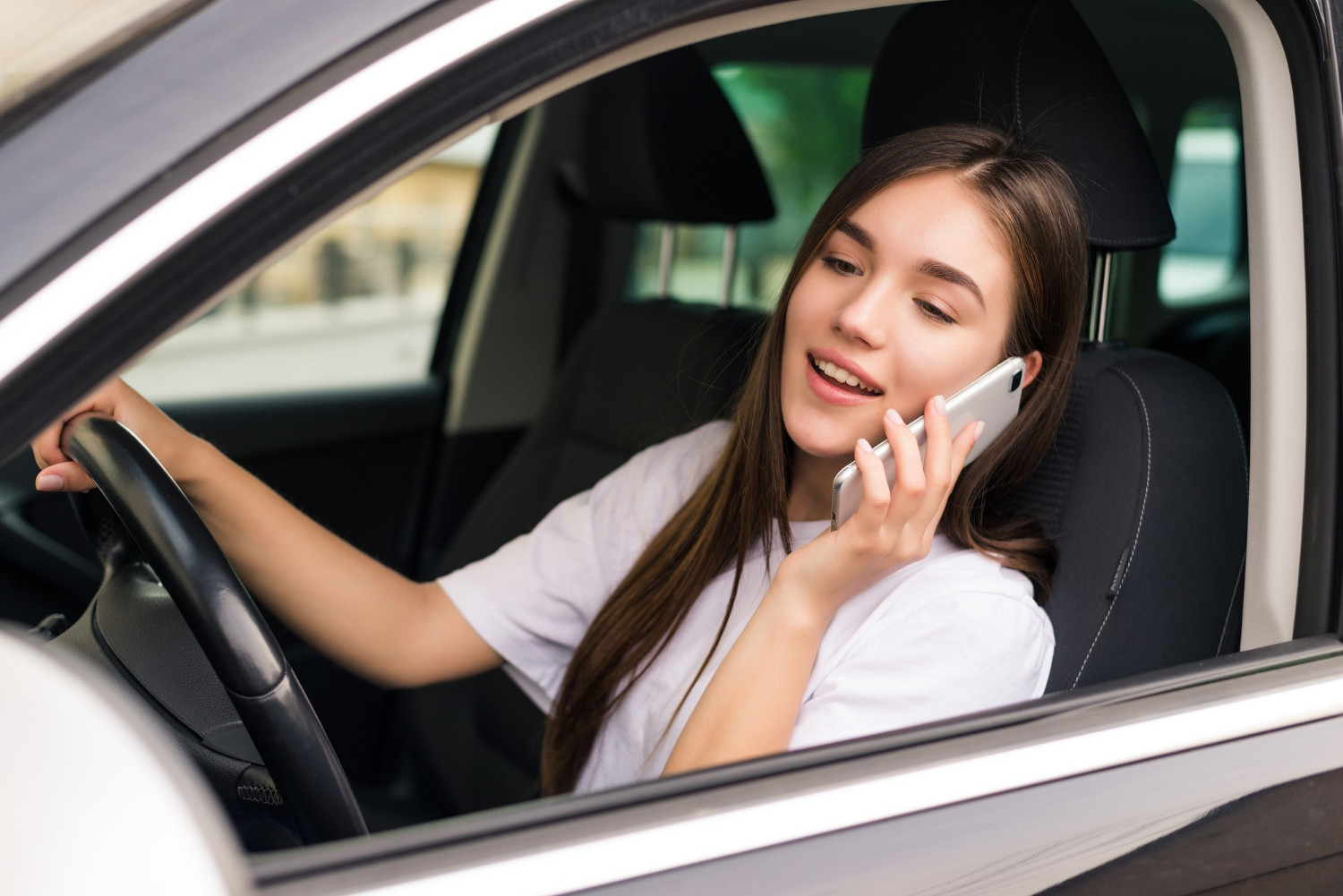 A delighted woman sitting in her car and talking on the phone | Source: Freepik