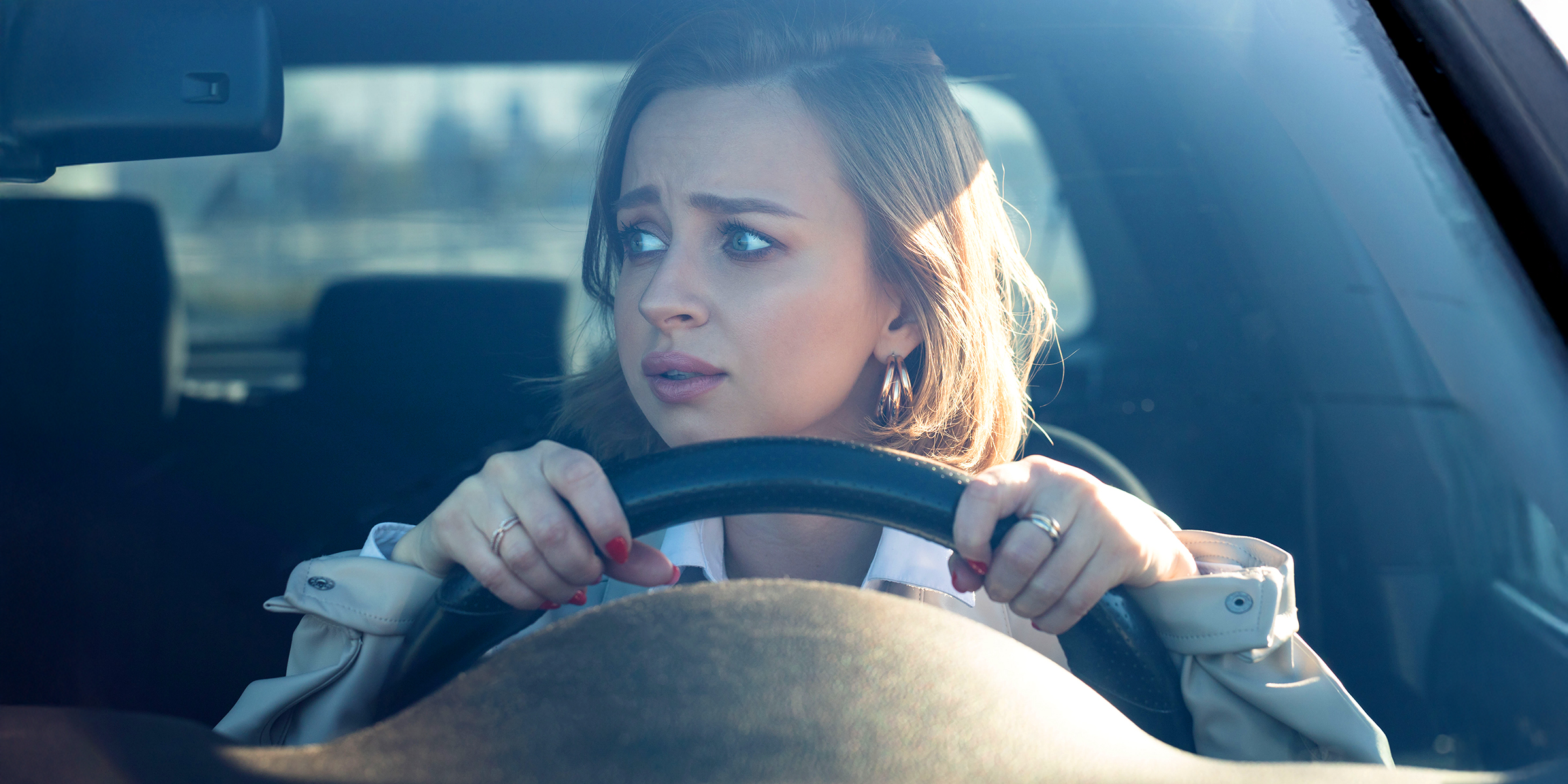 A young woman gripping the steering wheel, staring ahead with wide, anxious eyes | Source: Shutterstock