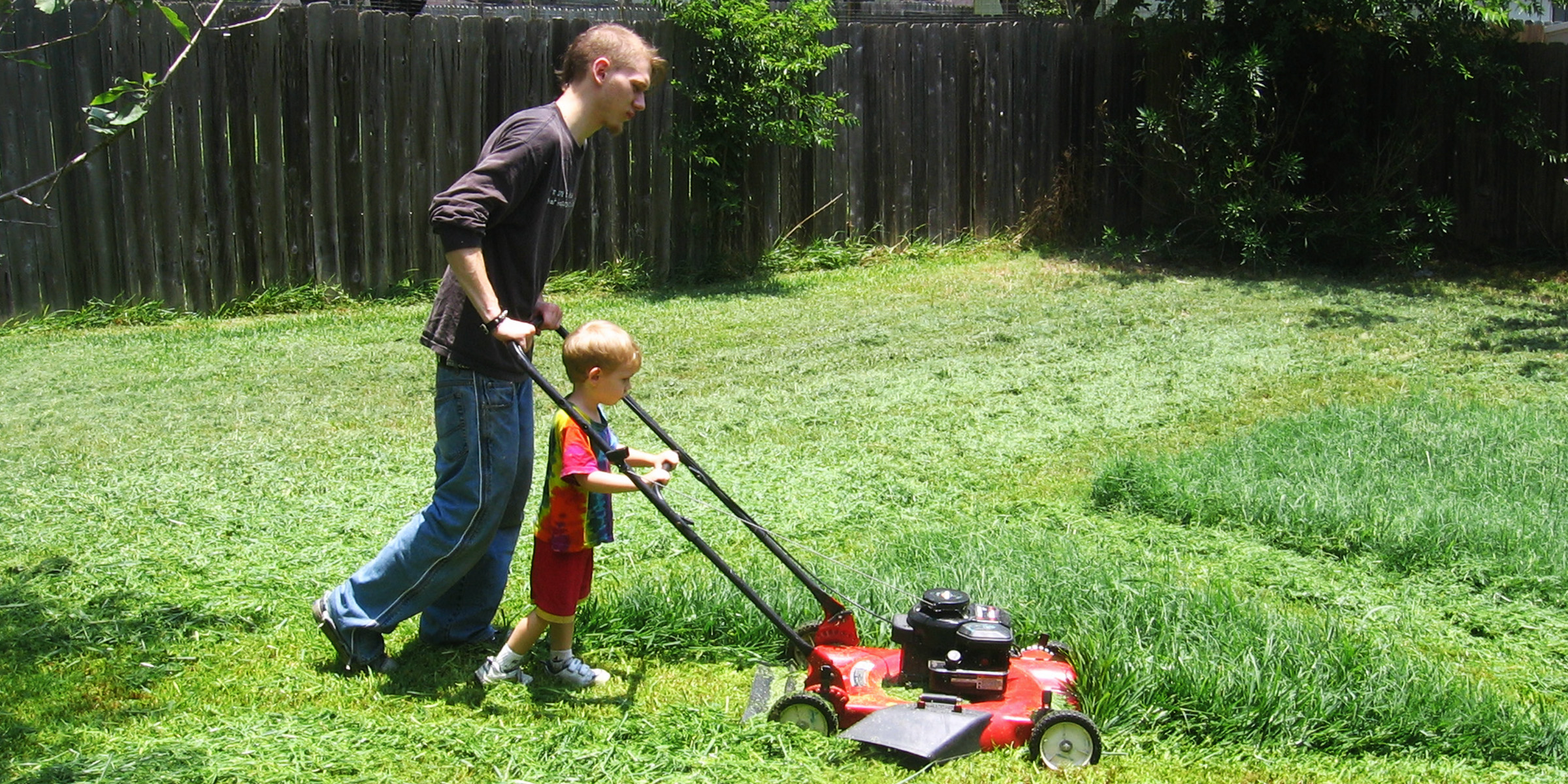 A man and his son mowing the lawn | Source: Flickr