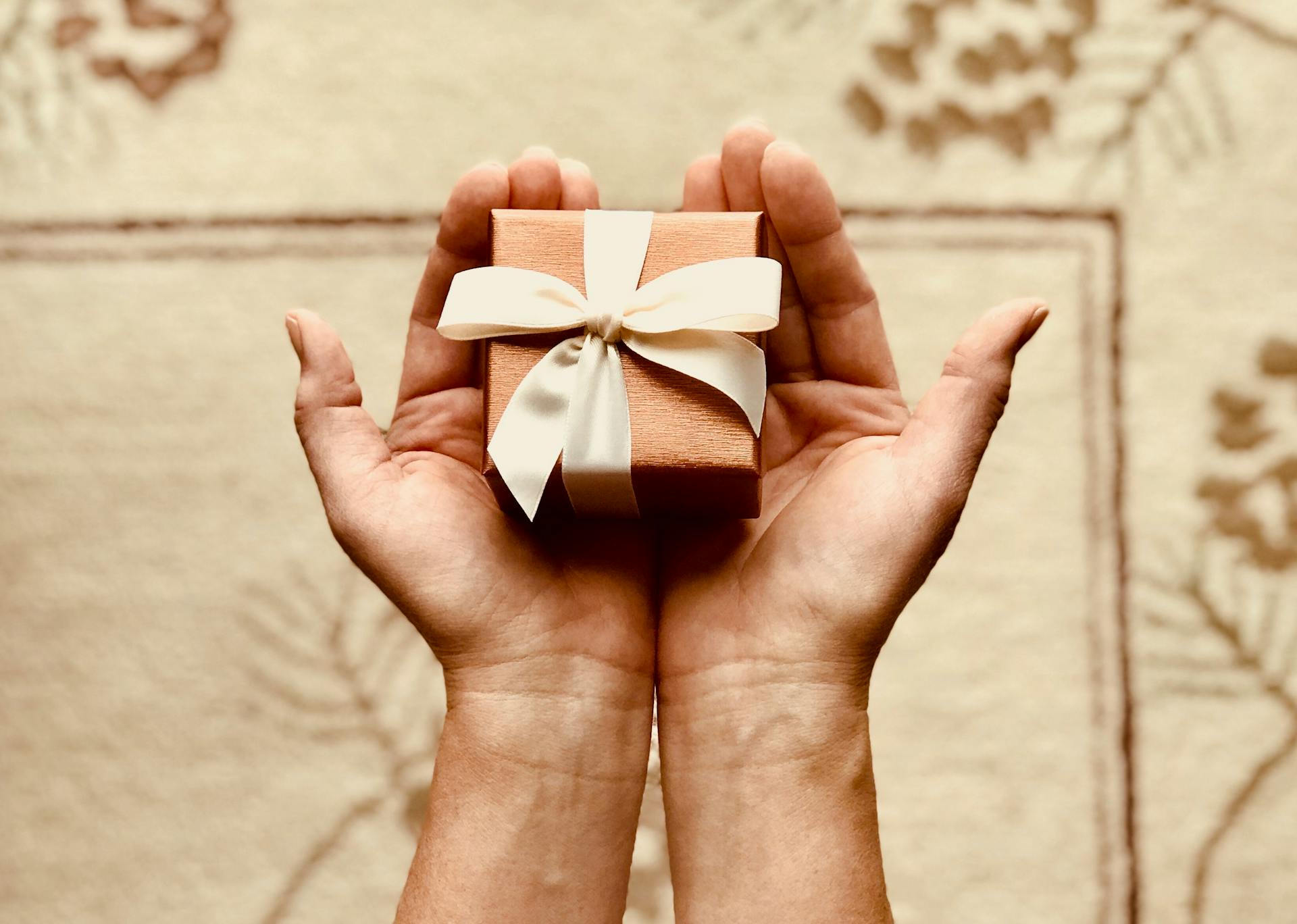 Close-up of a woman holding a small brown giftbox | Source: Pexels