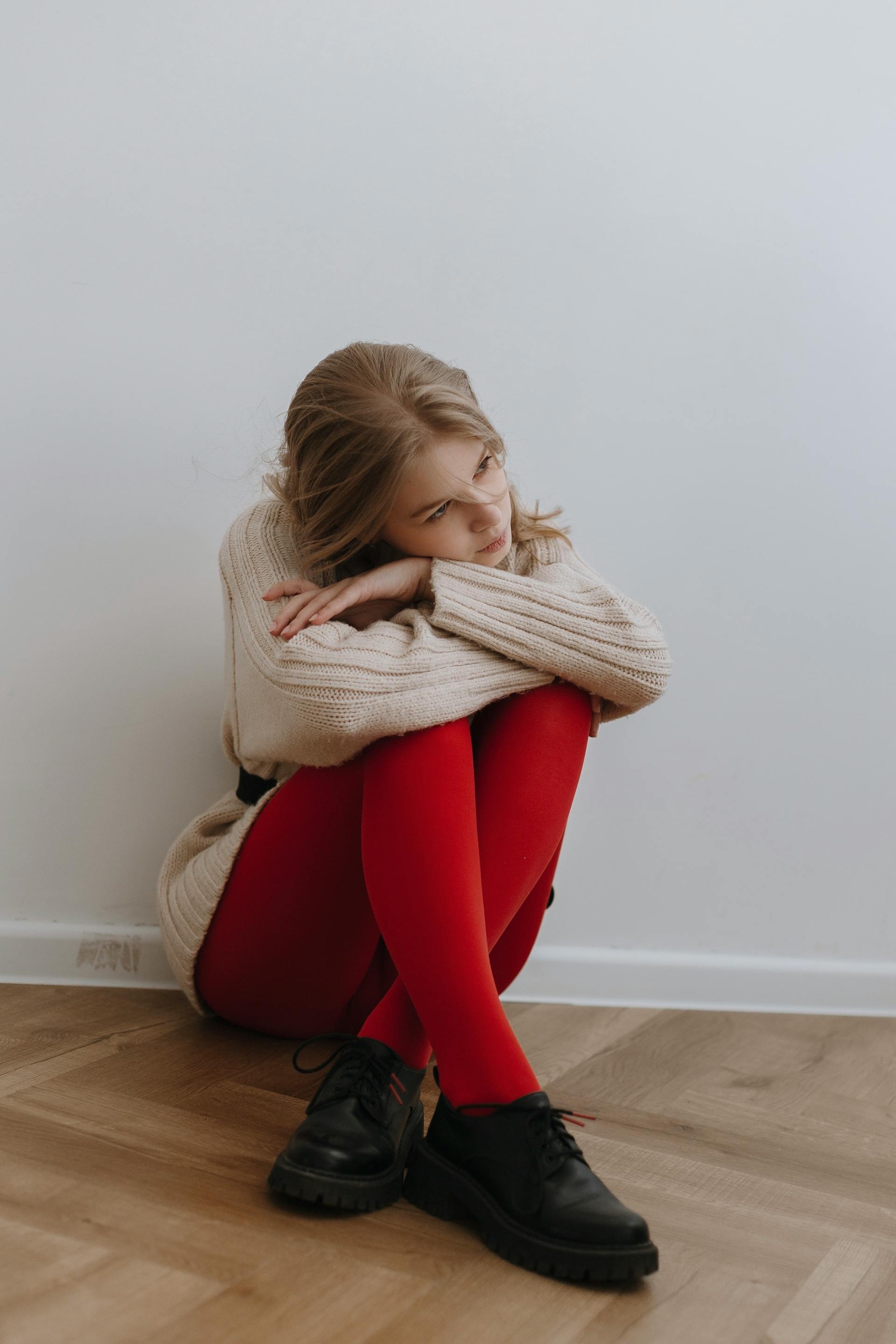 A tired woman sitting on the floor by a wall | Source: Pexels